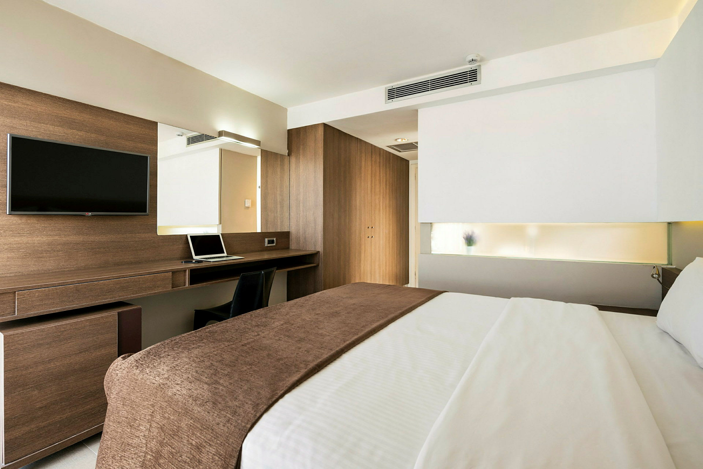 Ett modernt hotellrum med en dubbelsäng, ett skrivbord och en TV. (AI-genererad text)
