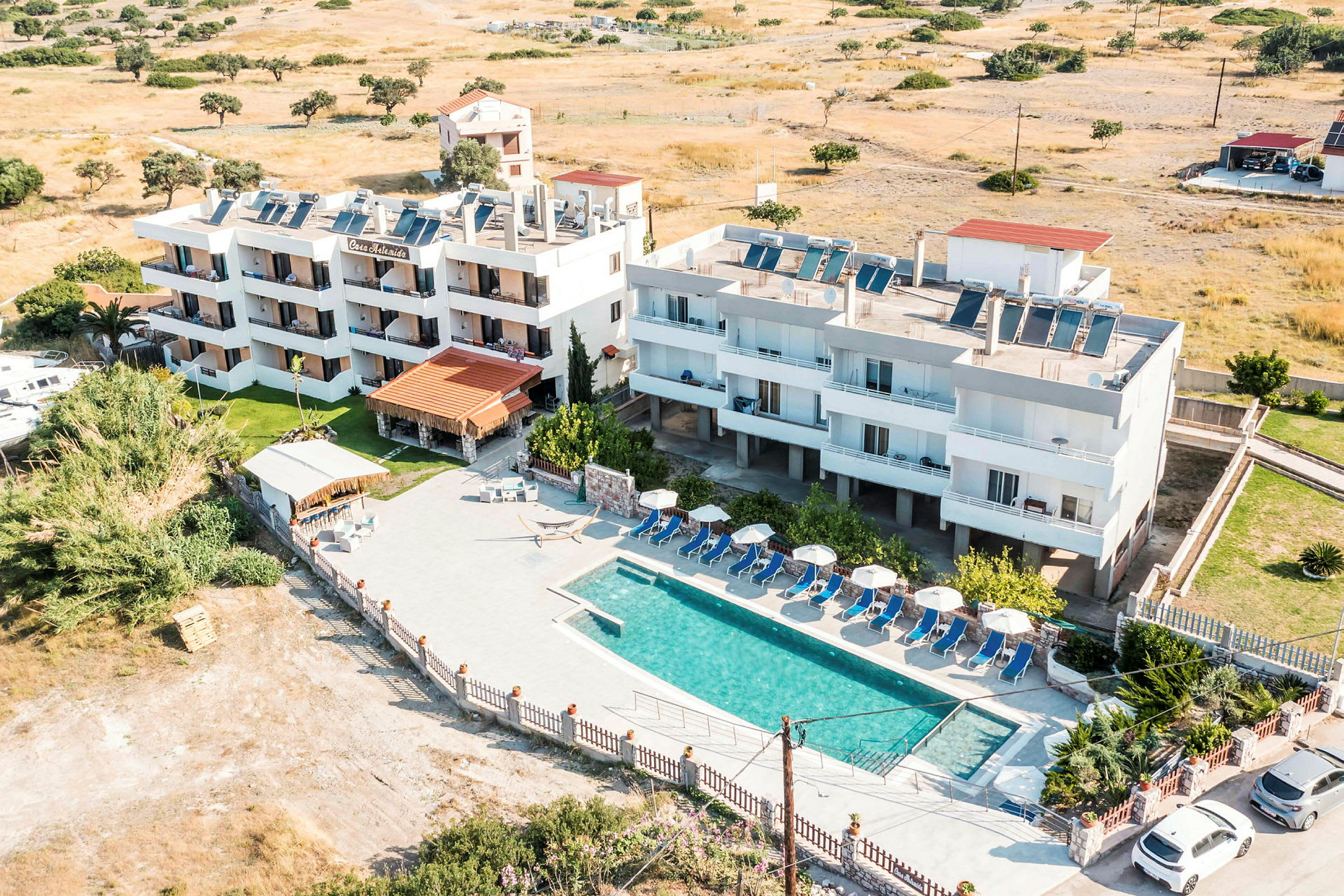 Bild av ett hotell med pool och solstolar samt omkringliggande landskap. (AI-genererad text)