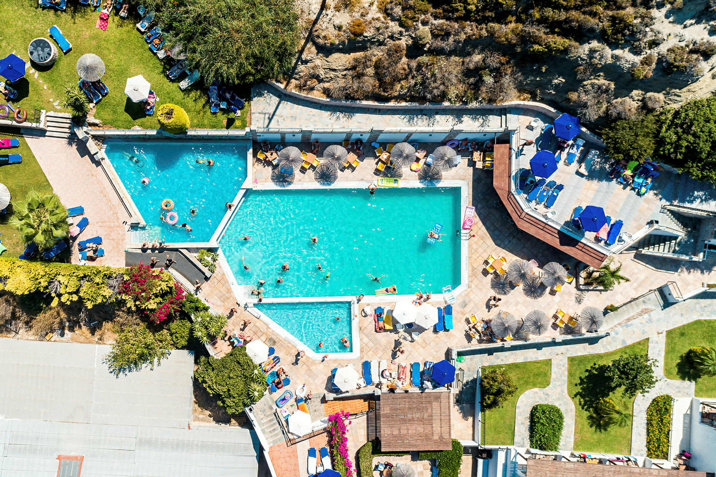 Flygfoto av en poolanläggning med människor och solstolar. (AI-genererad text)