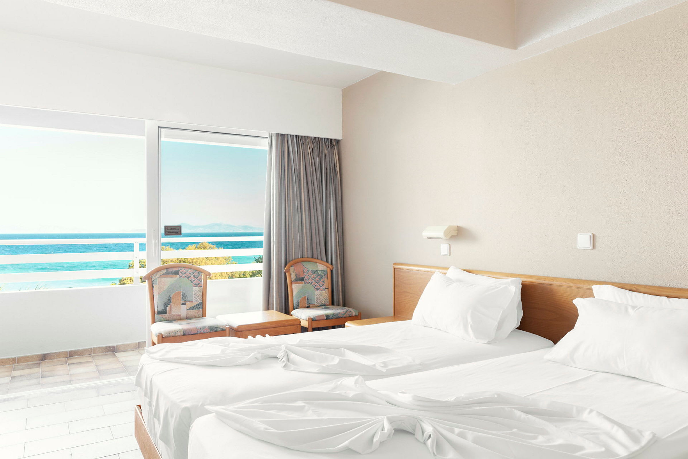 Ett hotellrum med två enkelsängar och en balkong med utsikt över havet. (AI-genererad text)