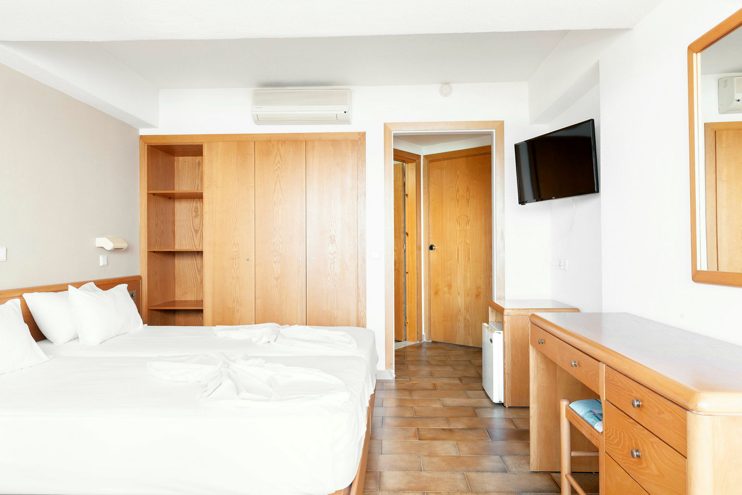 Hotellrum med två enkelsängar, garderob, skrivbord och spegel. (AI-genererad text)