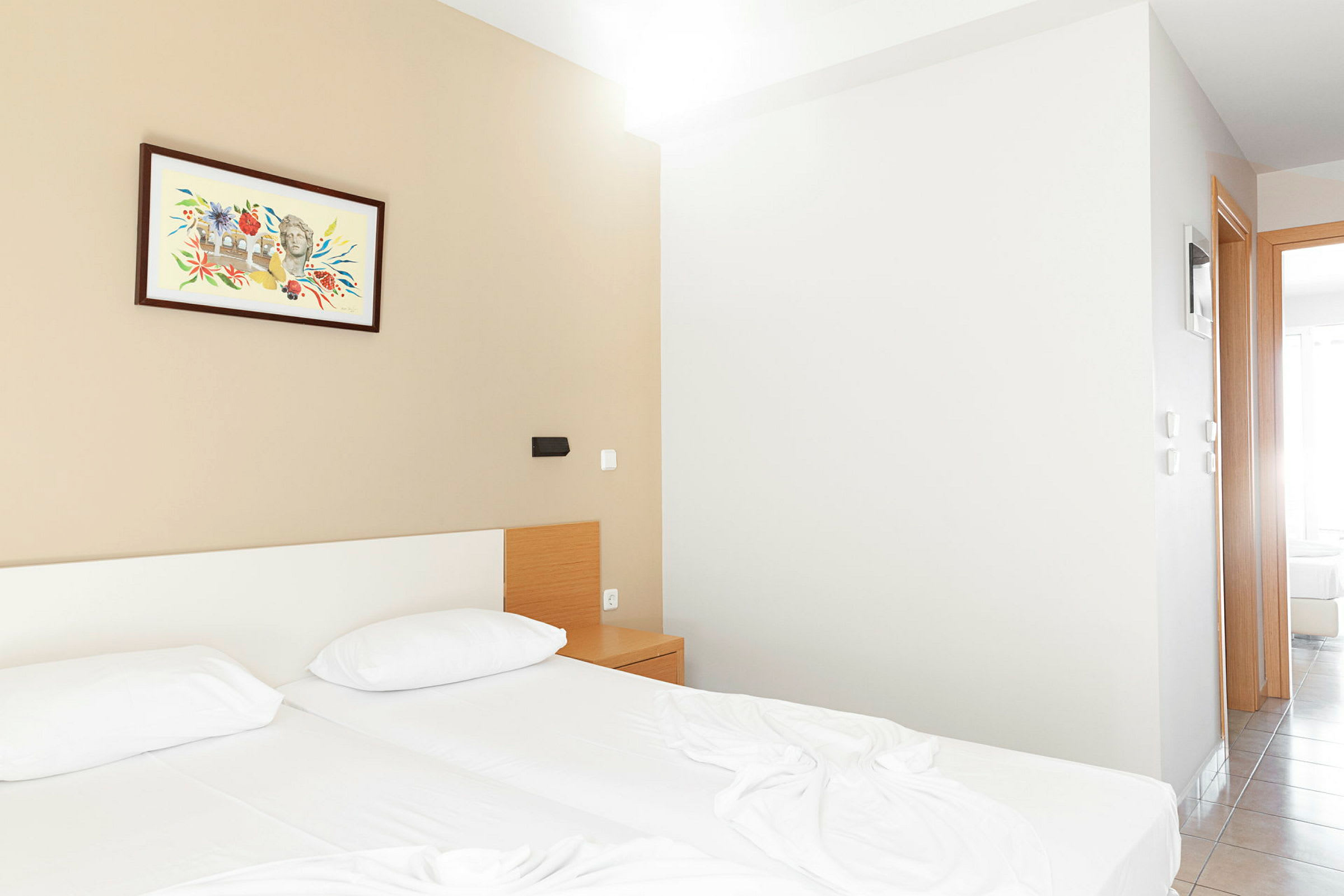 Ett hotellrum med två sängar, ett nattduksbord och en målning på väggen. (AI-genererad text)
