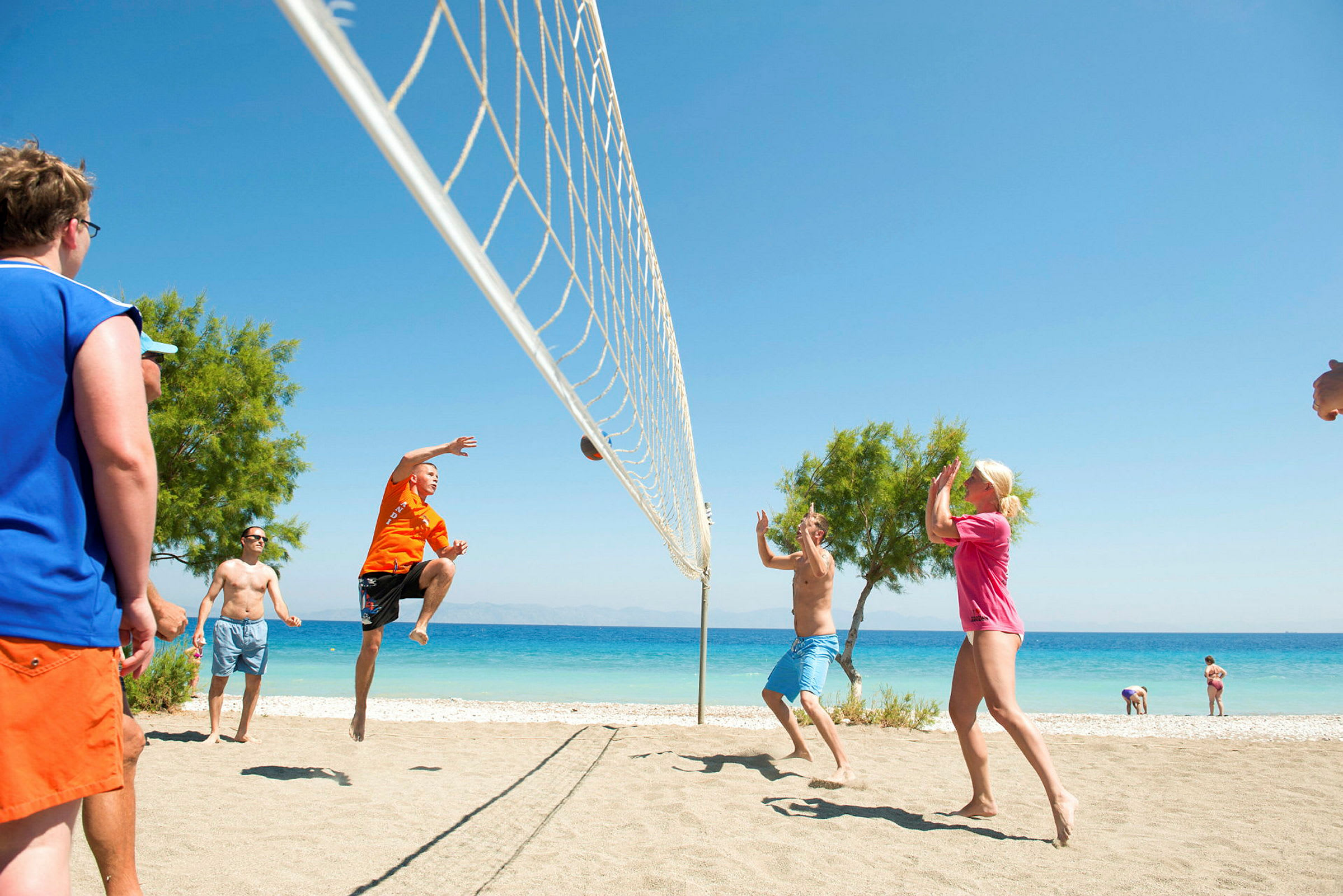 Personer spelar volleyboll på en sandstrand nära havet. (AI-genererad text)