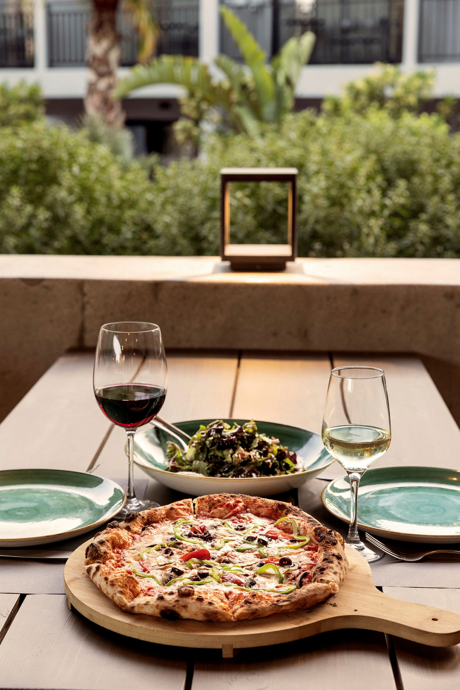Ett bord med en pizza, en skål med sallad, två vinglas och tallrikar. (AI-genererad text)