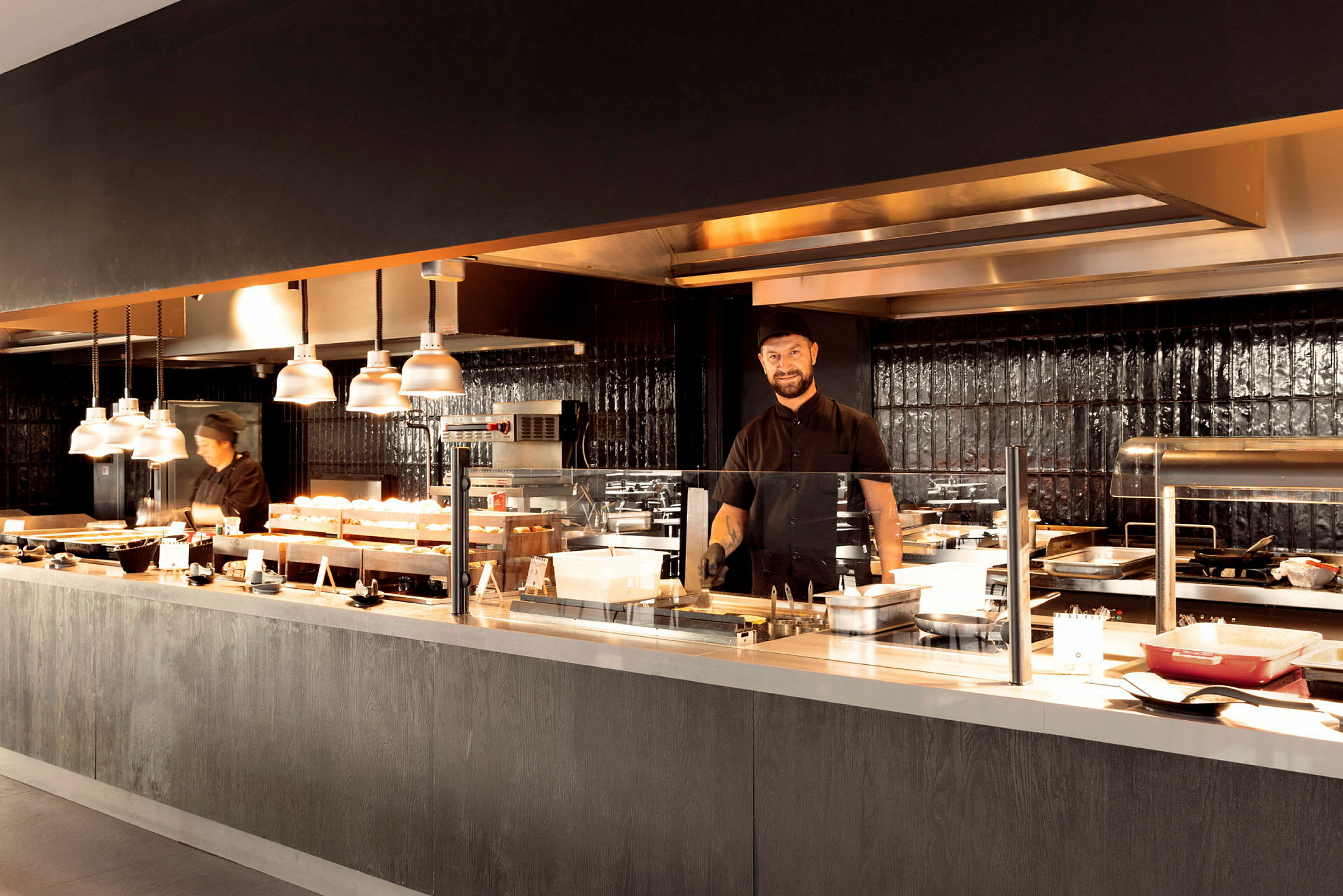 Ett restaurangkök med flera matstationer och belysning. (AI-genererad text)