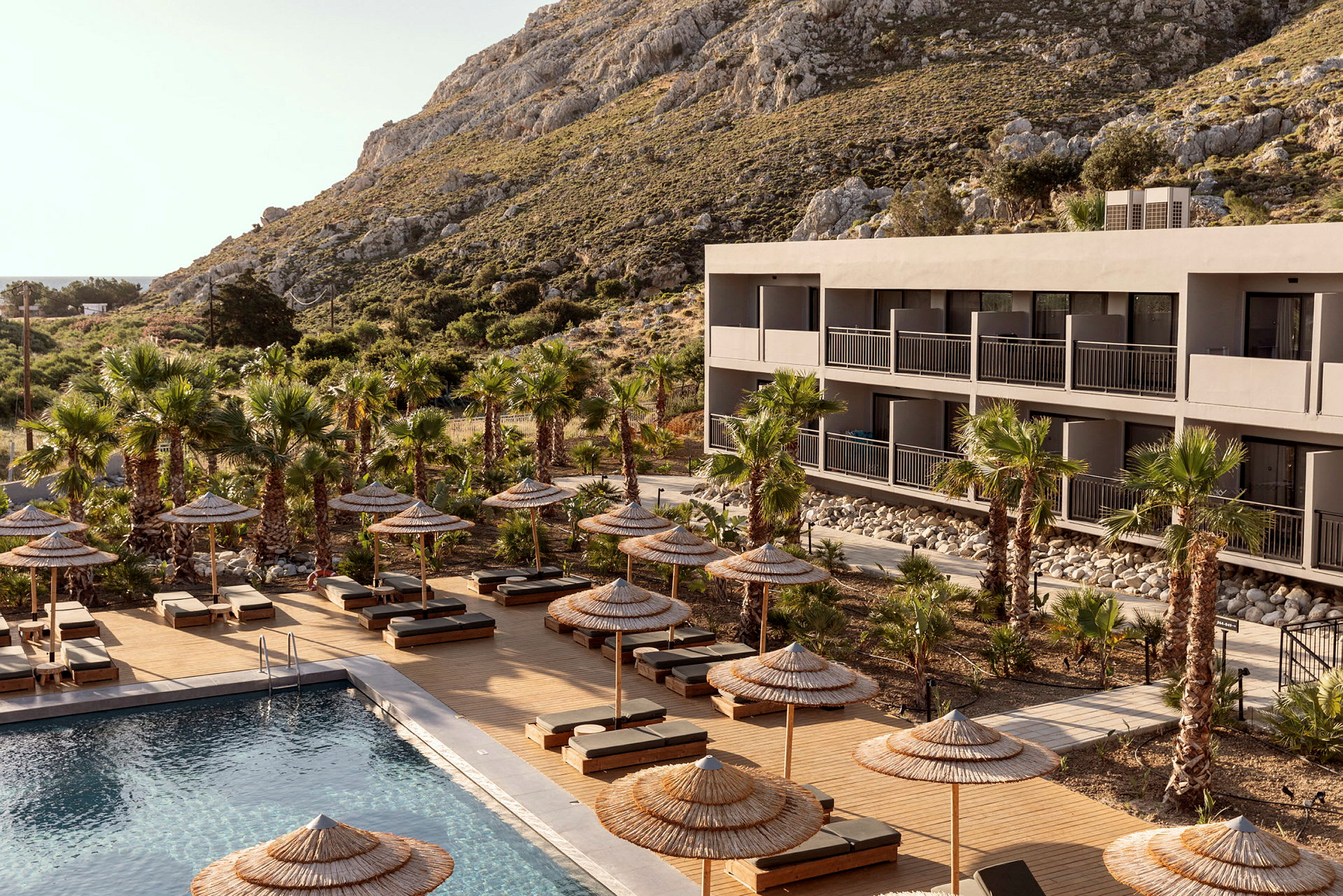 Hotellbyggnad med pool och solstolar omgivna av palmer. (AI-genererad text)