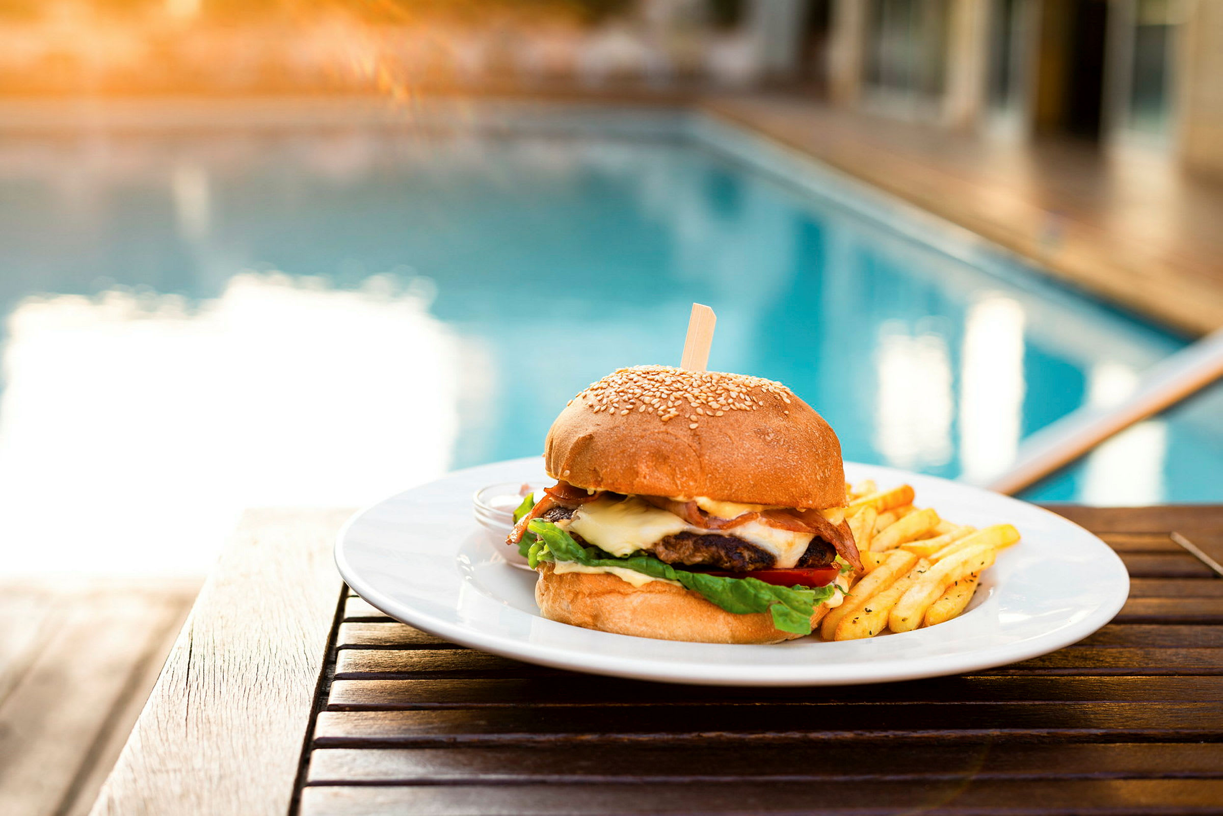 En tallrik med hamburgare och pommes frites vid en pool. (AI-genererad text)