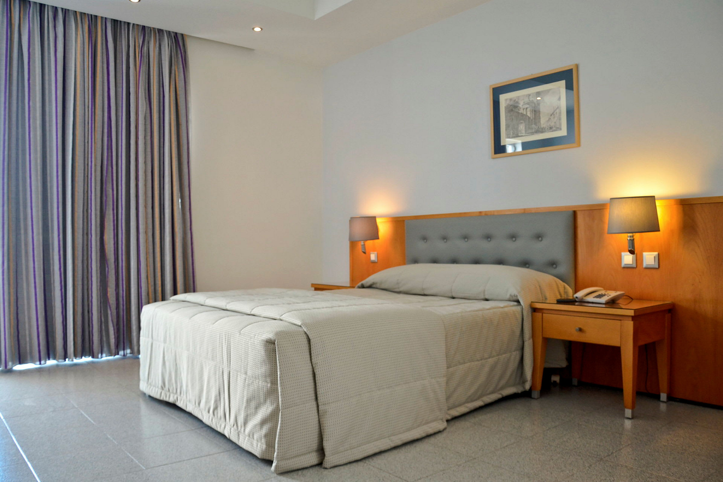 Hotellrum med en säng och två sänglampor. (AI-genererad text)