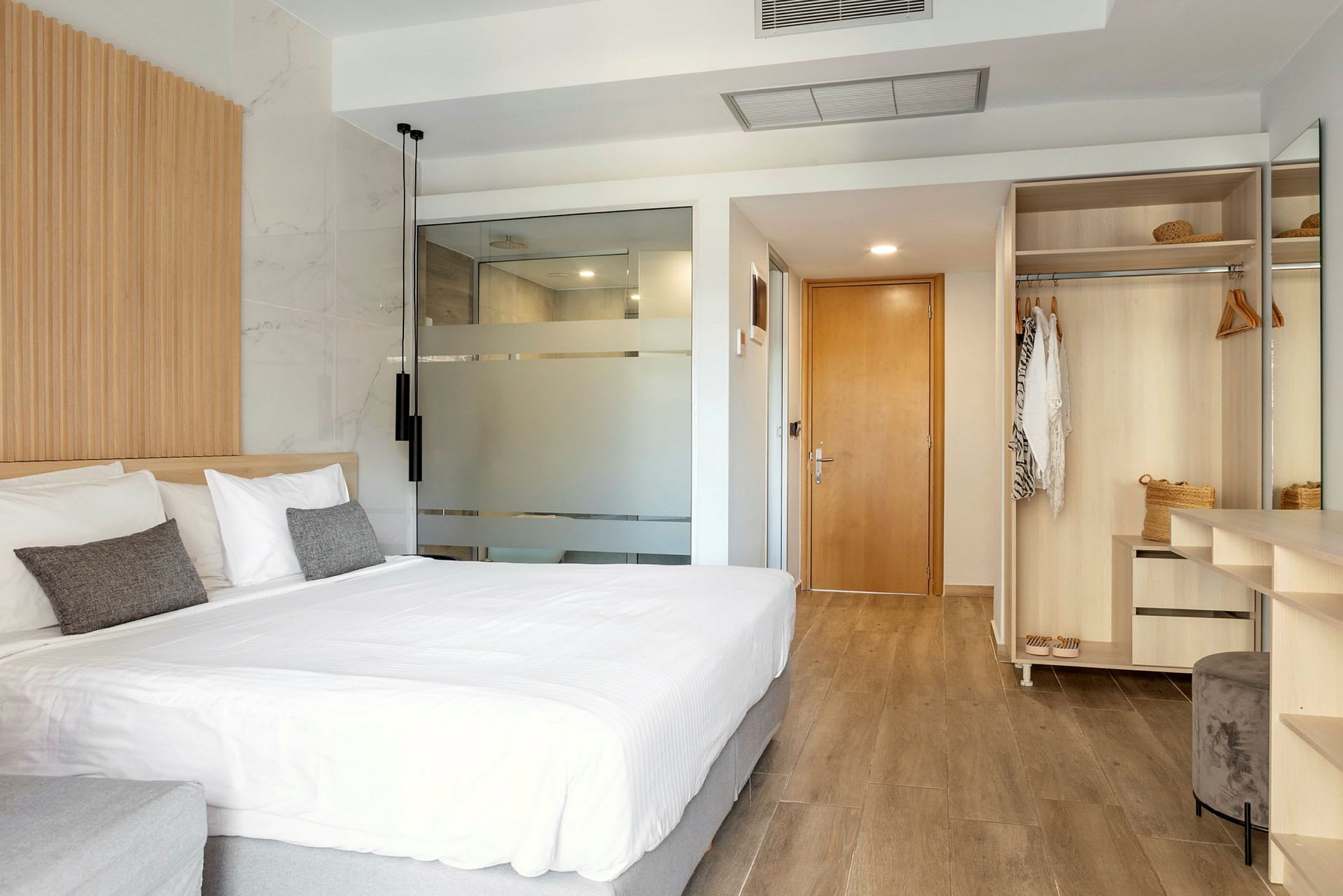 Ett modernt hotellrum med stor säng, garderob och badrumsdörr. (AI-genererad text)