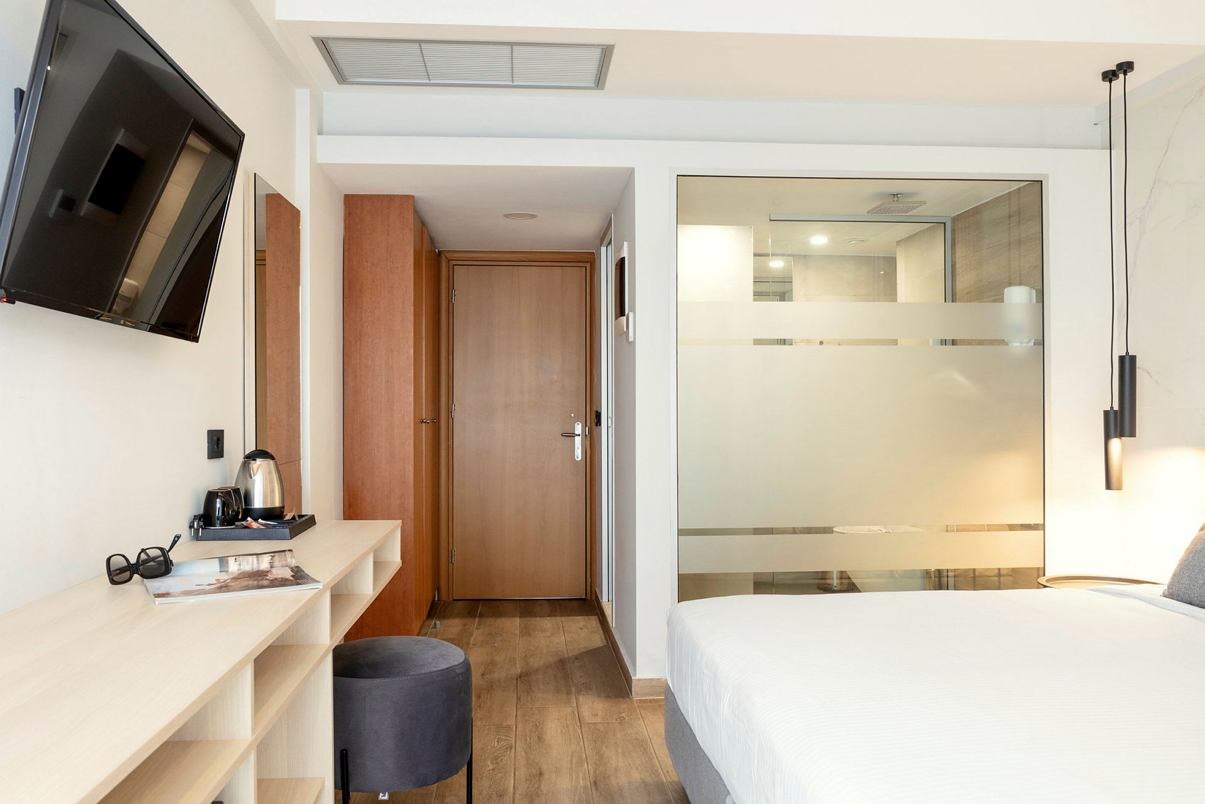 Modernt hotellrum med säng, skrivbord och TV. (AI-genererad text)