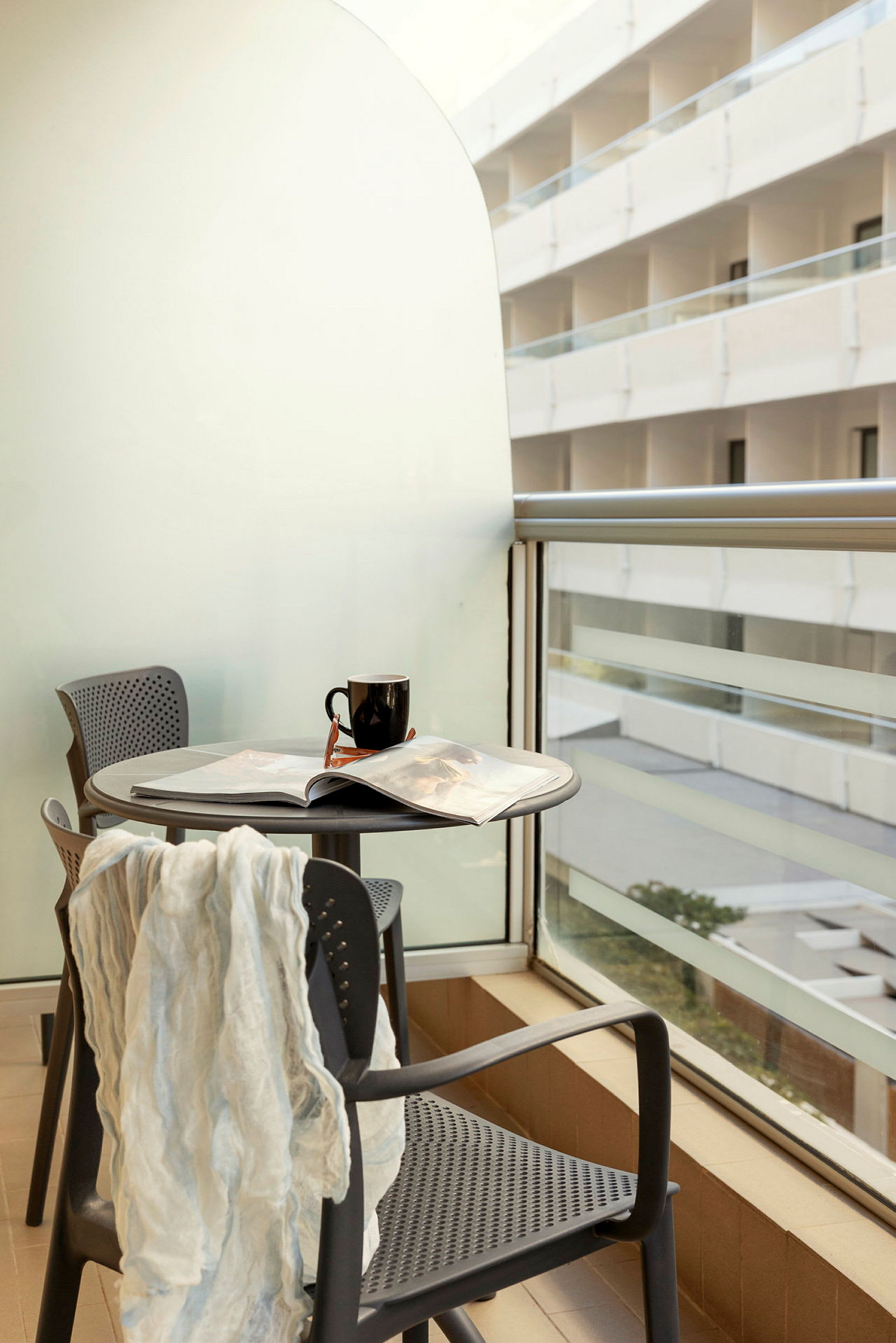 Uteplats med bord och två stolar samt en svart kaffemugg och en öppen tidning. (AI-genererad text)