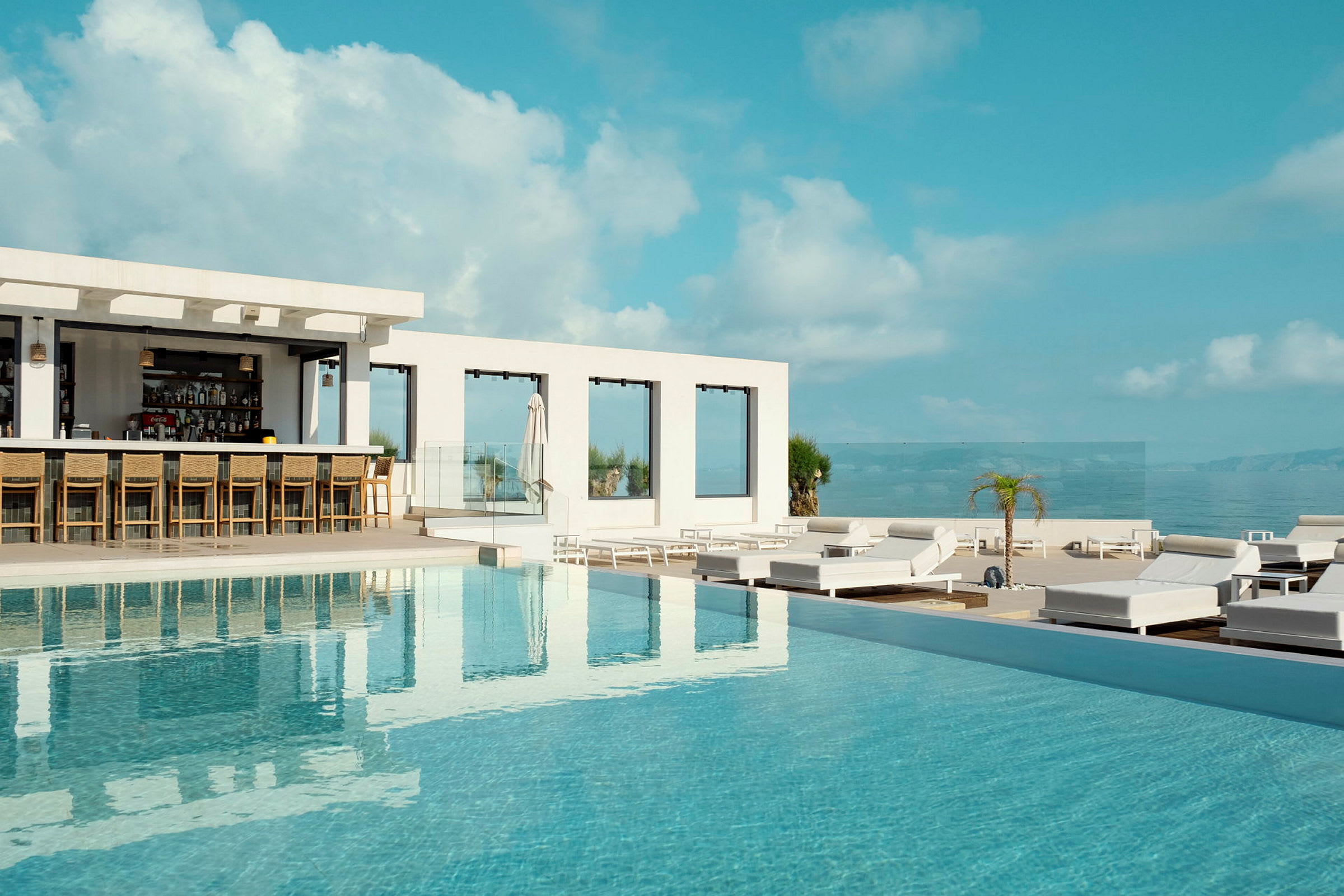 Utomhuspool vid en resort med en bar och solstolar. (AI-genererad text)