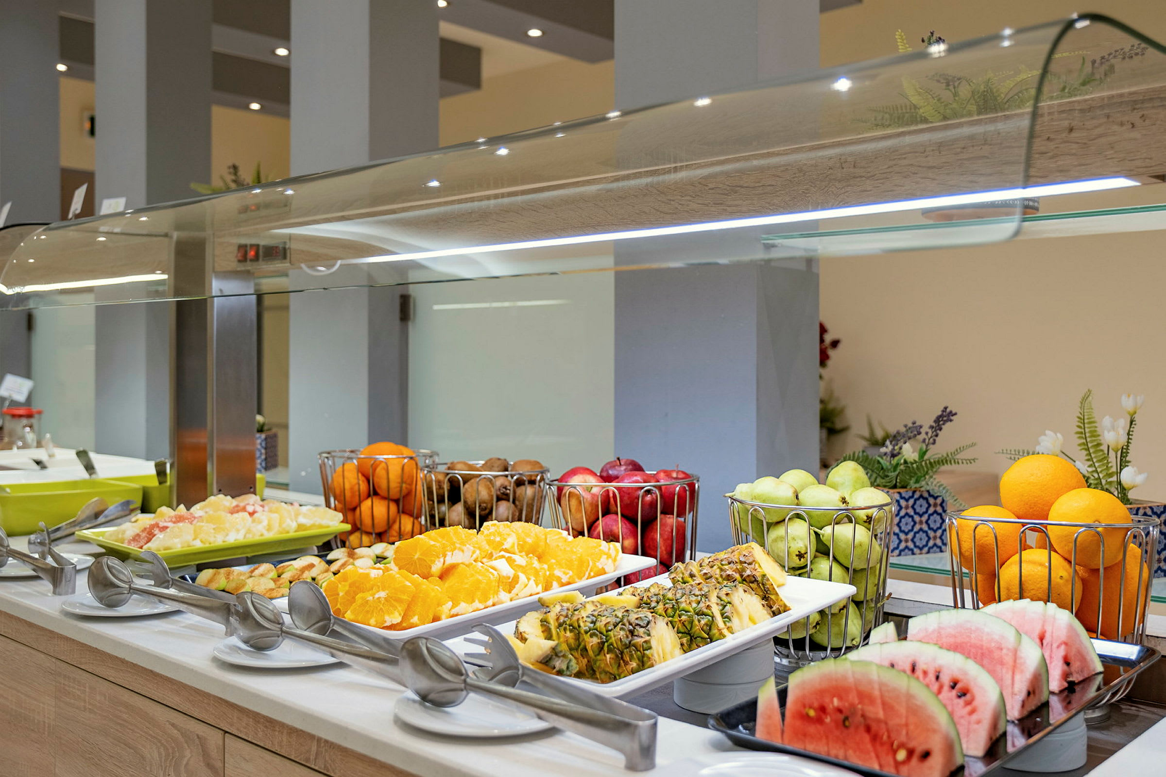 En buffé med olika frukter, inklusive skivad vattenmelon och ananas, apelsiner, samt druvor. (AI-genererad text)