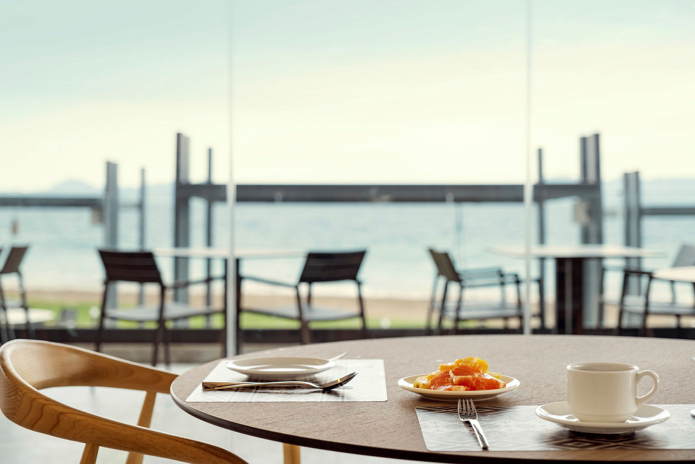 En tallrik med frukt och en kopp på ett bord, med utsikt över stranden. (AI-genererad text)