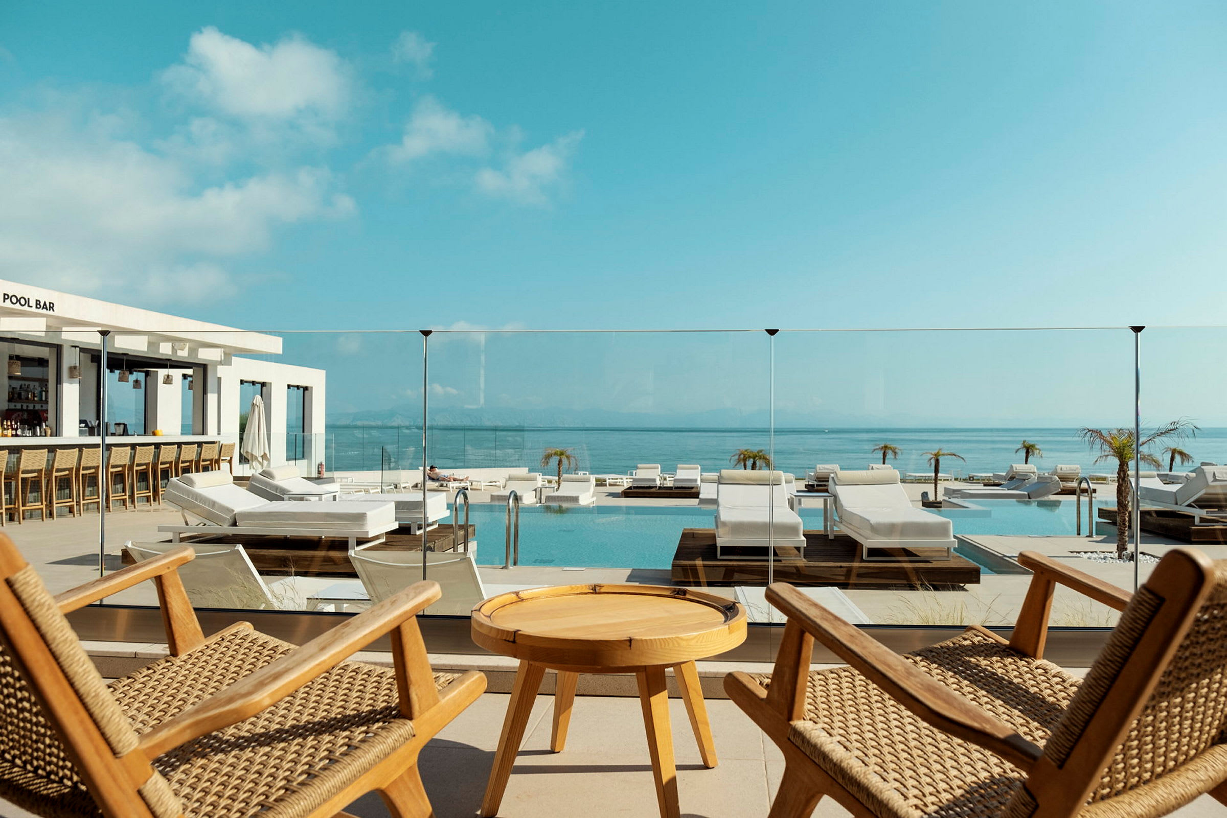 Utsikt över en pool med solstolar och panoramavy av havet. (AI-genererad text)