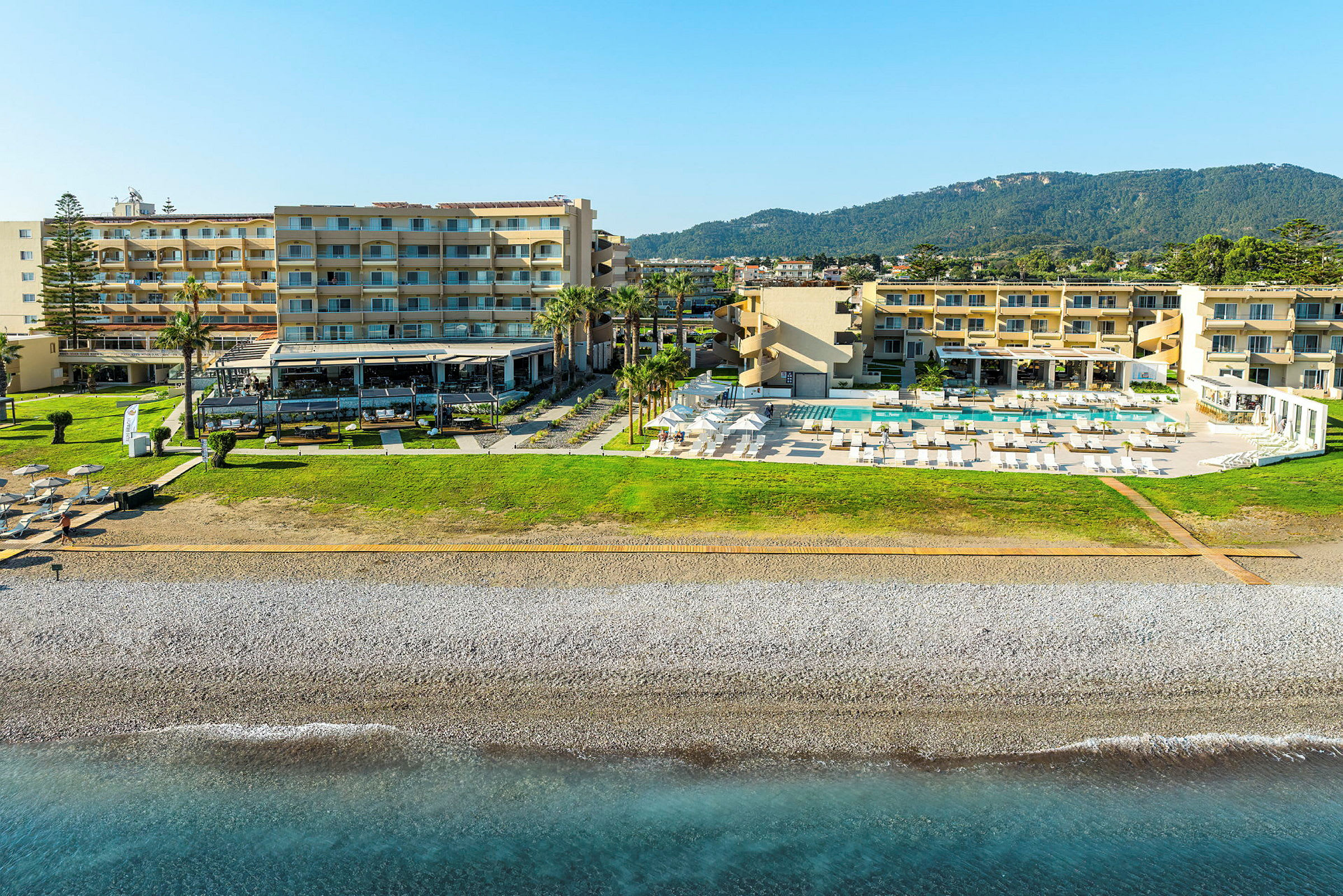 Hotellbyggnader med pool och solstolar vid havet. (AI-genererad text)