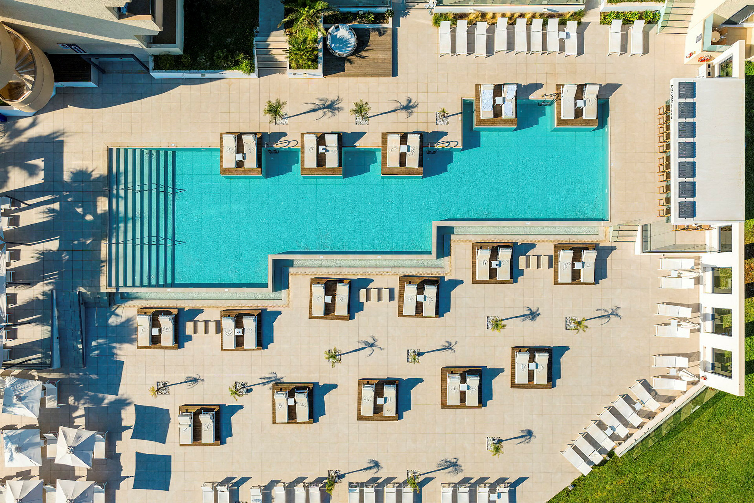 Fågelperspektiv av en poolområde med solstolar och cabanas. (AI-genererad text)