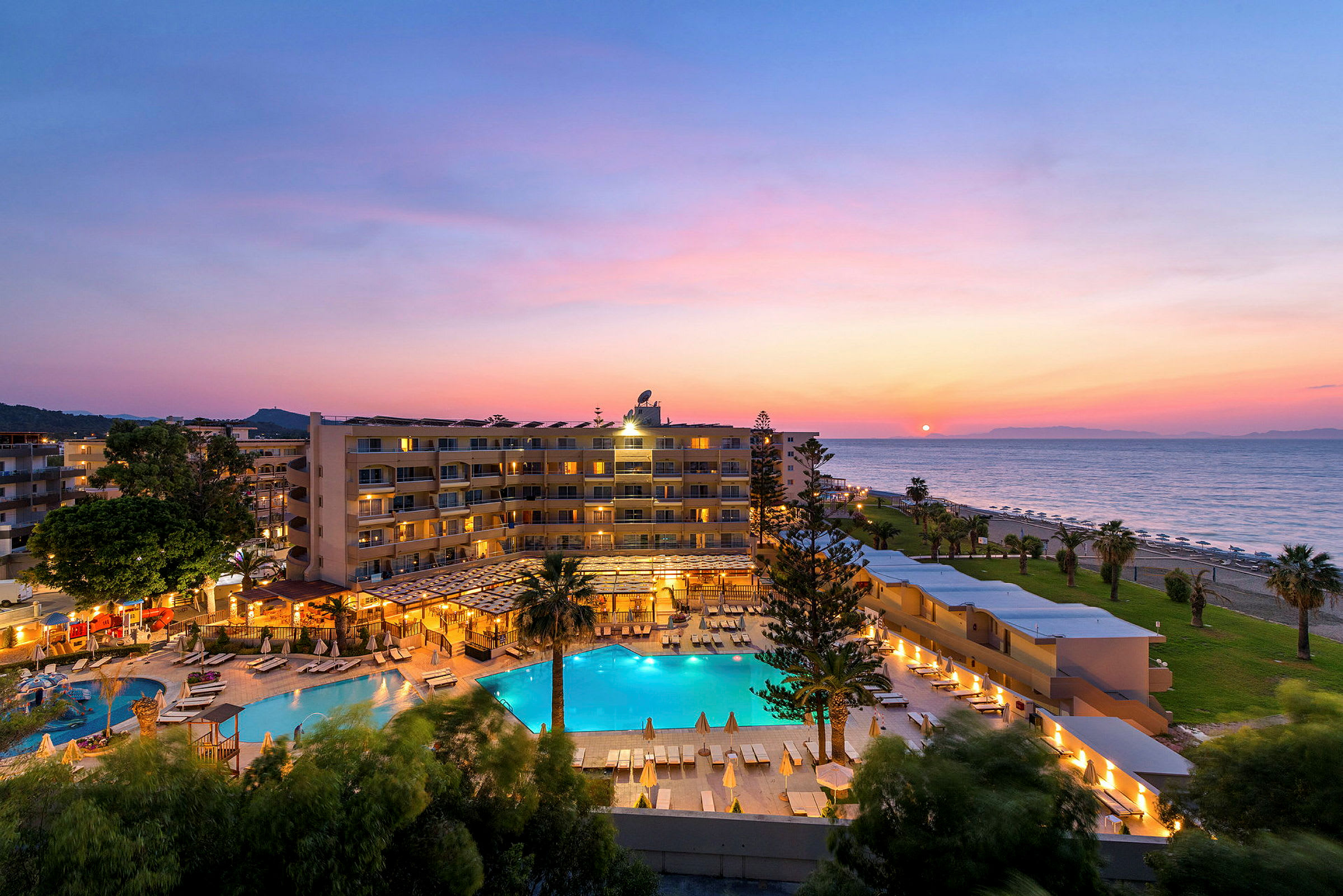 Hotellanläggning med pool, nära stranden vid solnedgång. (AI-genererad text)