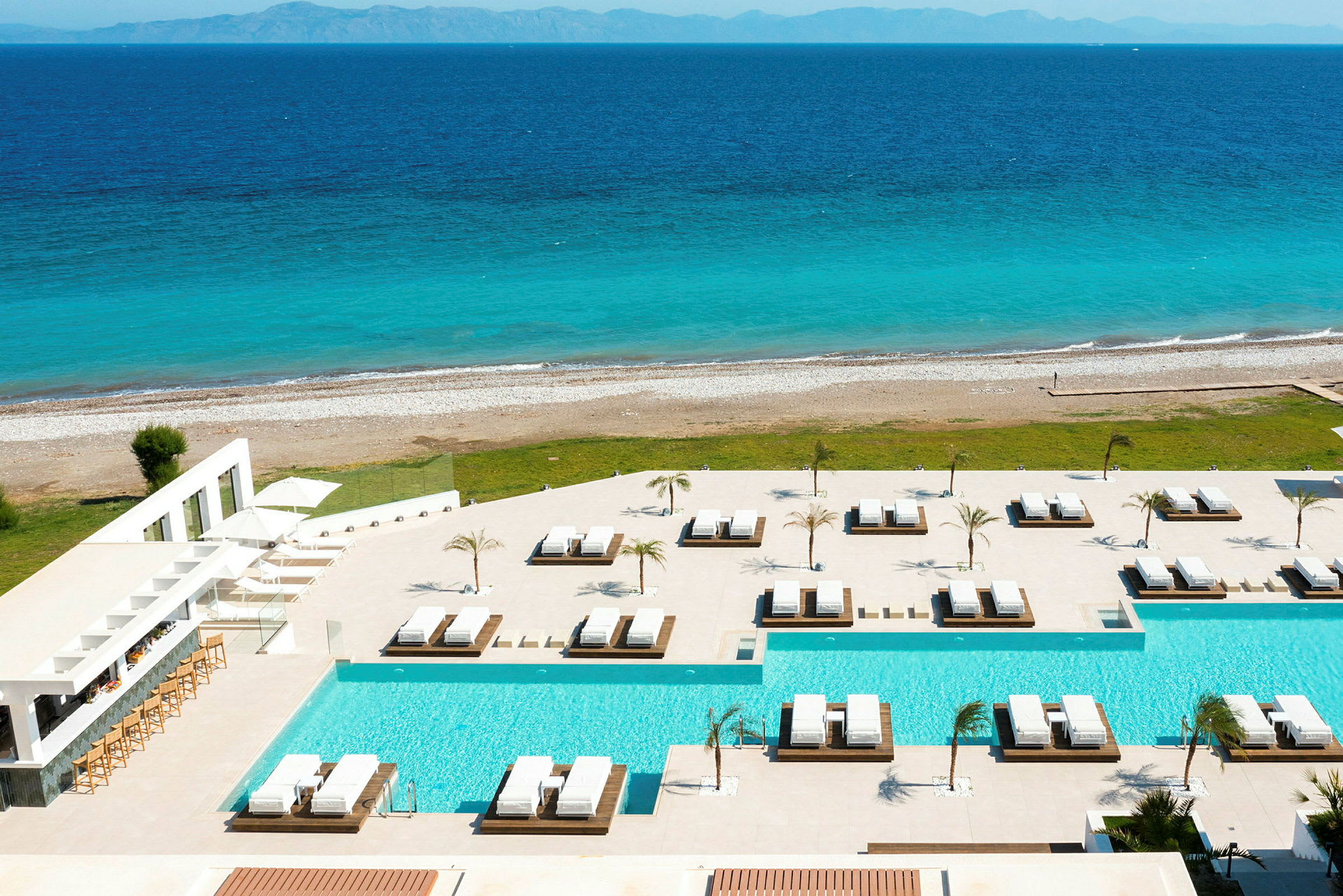 Bild på en pool och solstolar nära havet. (AI-genererad text)