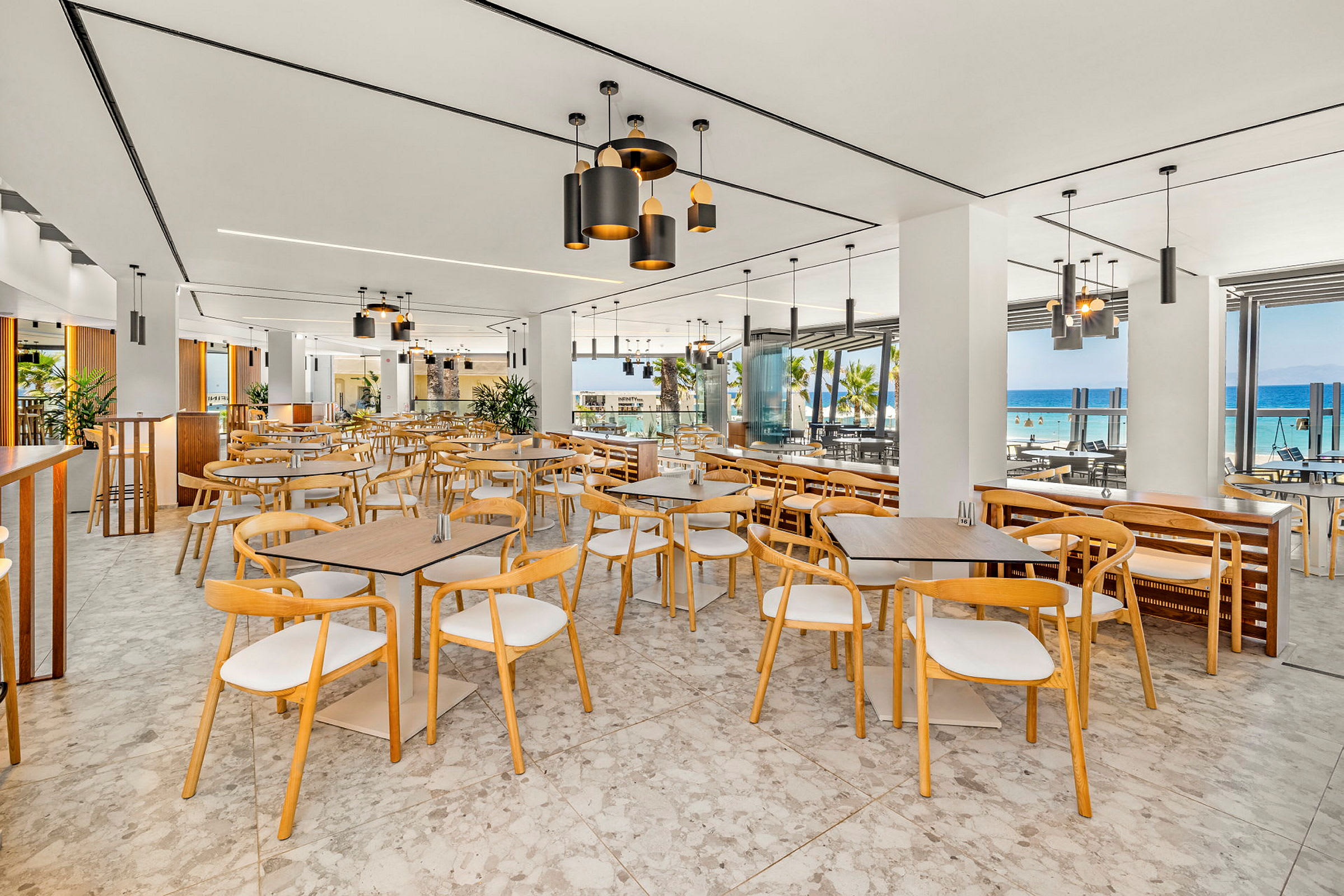 Restaurang med moderna möbler och stora fönster med utsikt över havet. (AI-genererad text)