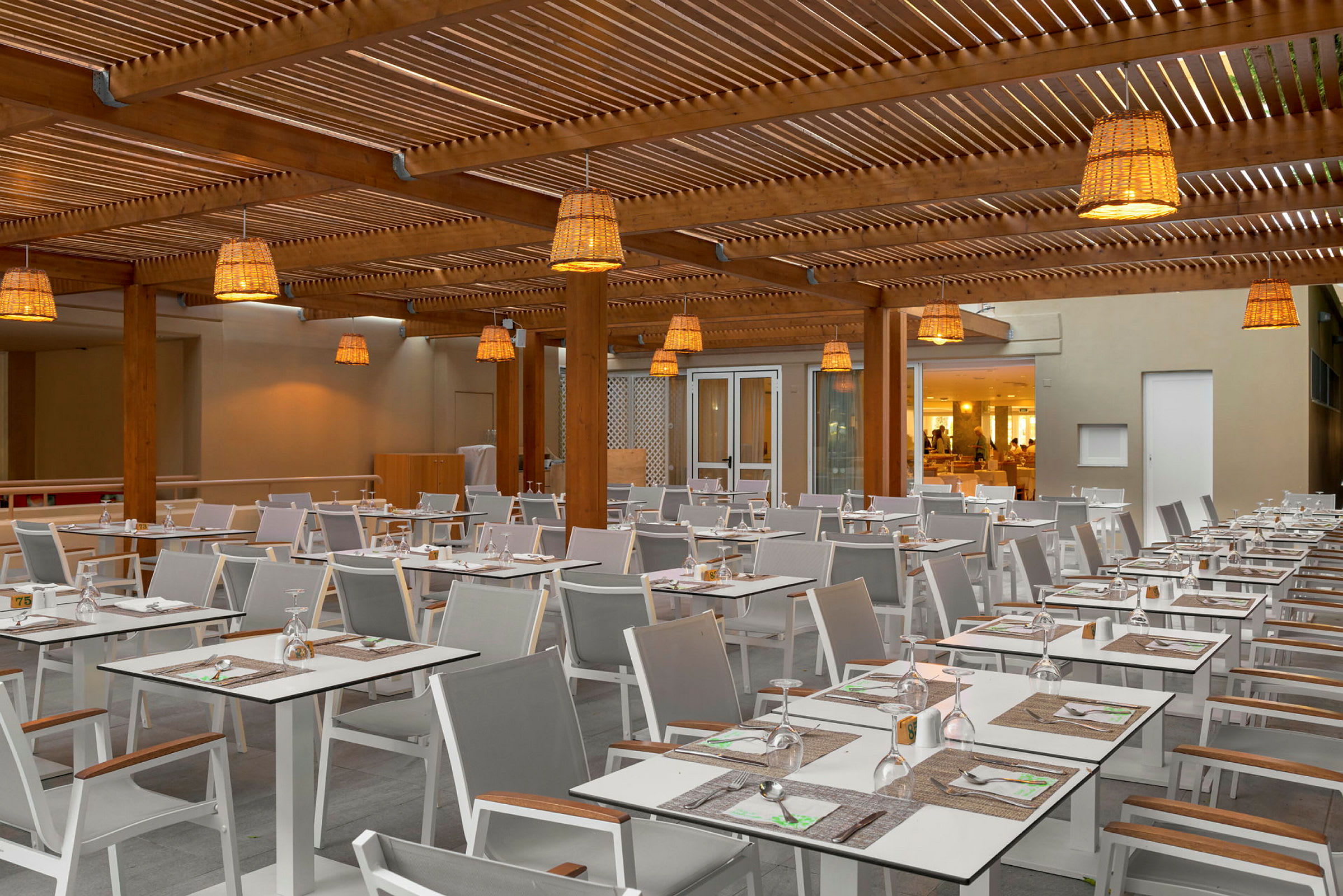 En utomhusrestaurang med bord och stolar, dekorerad med hängande lampor. (AI-genererad text)