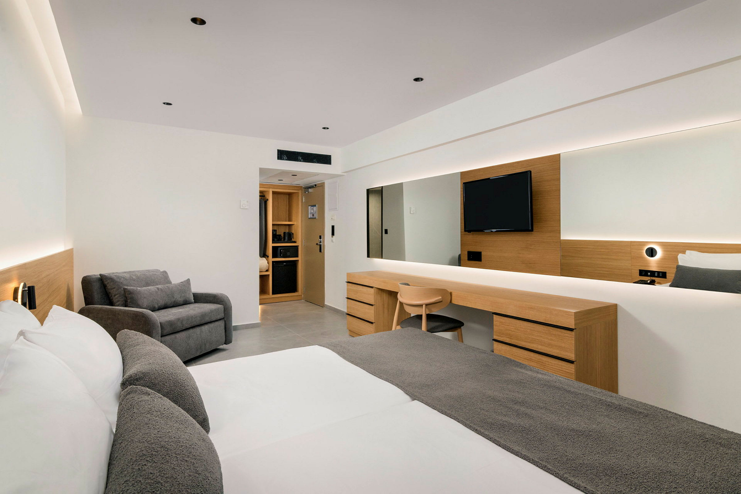 Ett modernt hotellrum med dubbelsäng, skrivbord, sittområde och TV. (AI-genererad text)