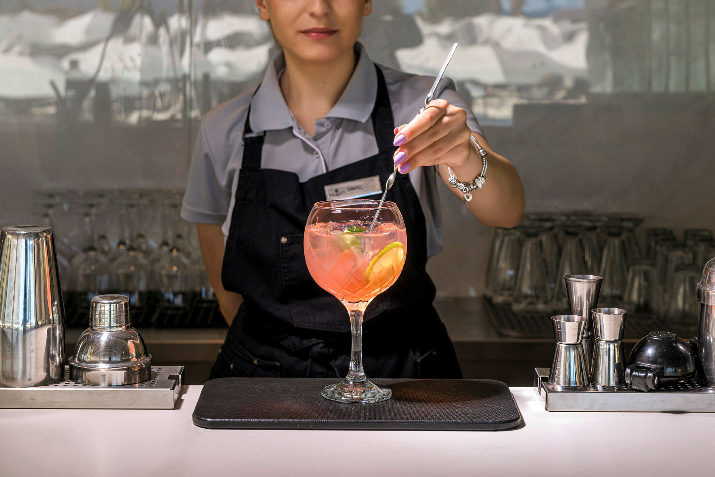 En bartender rör om i en drink med citronskivor och isbitar. (AI-genererad text)