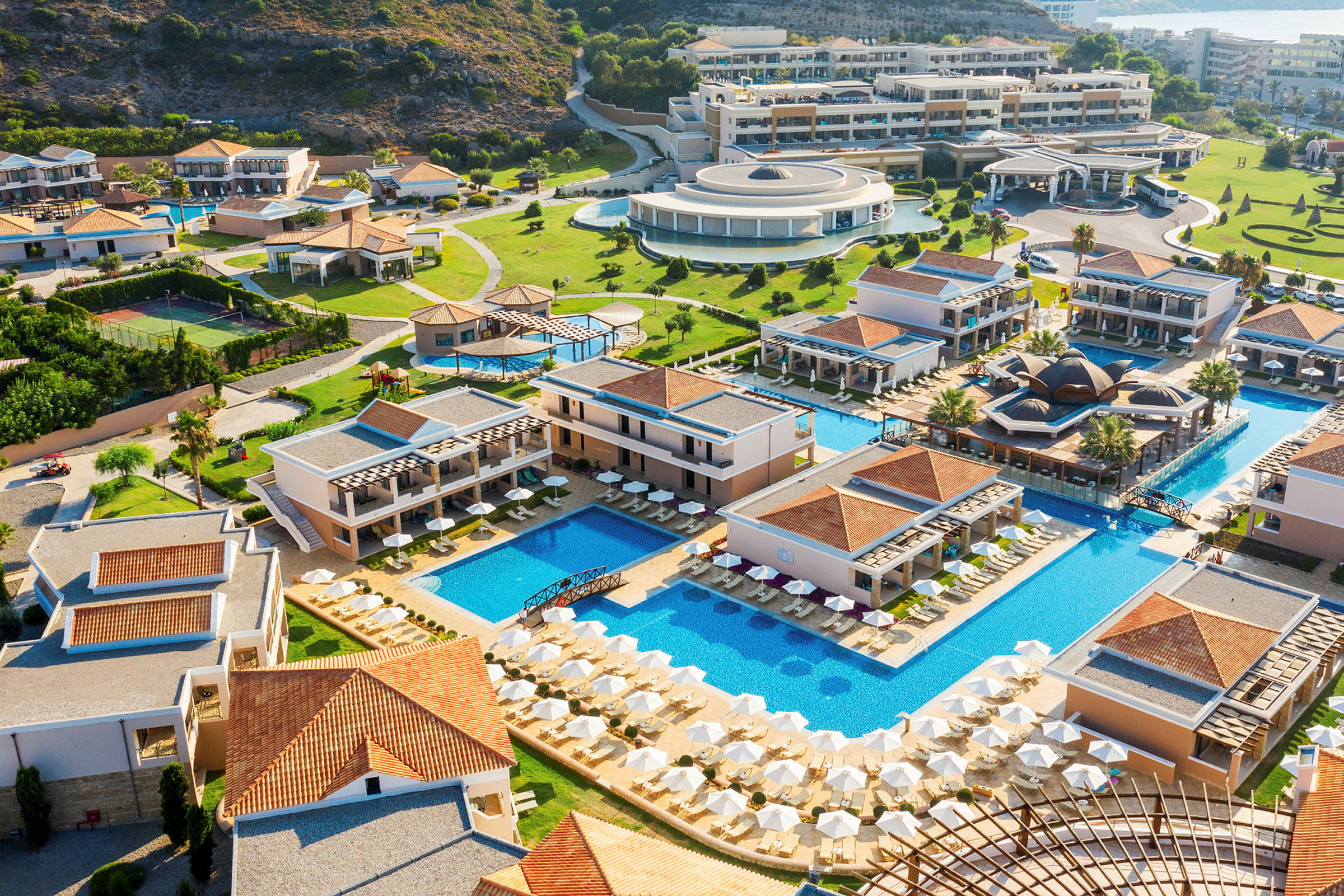 Flygfoto av en resort med pooler, byggnader och grönområden. (AI-genererad text)