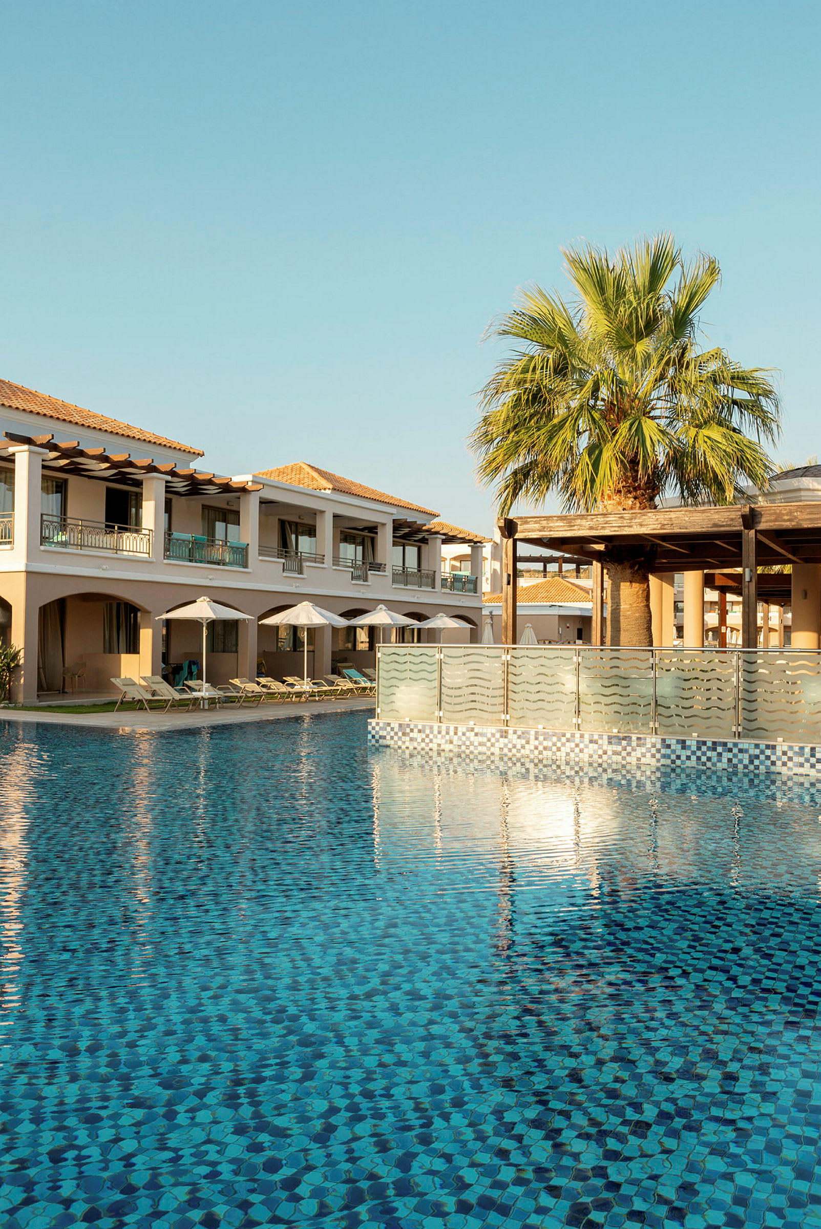 Bild av en klart blå pool omgiven av byggnader och en grön palm. (AI-genererad text)