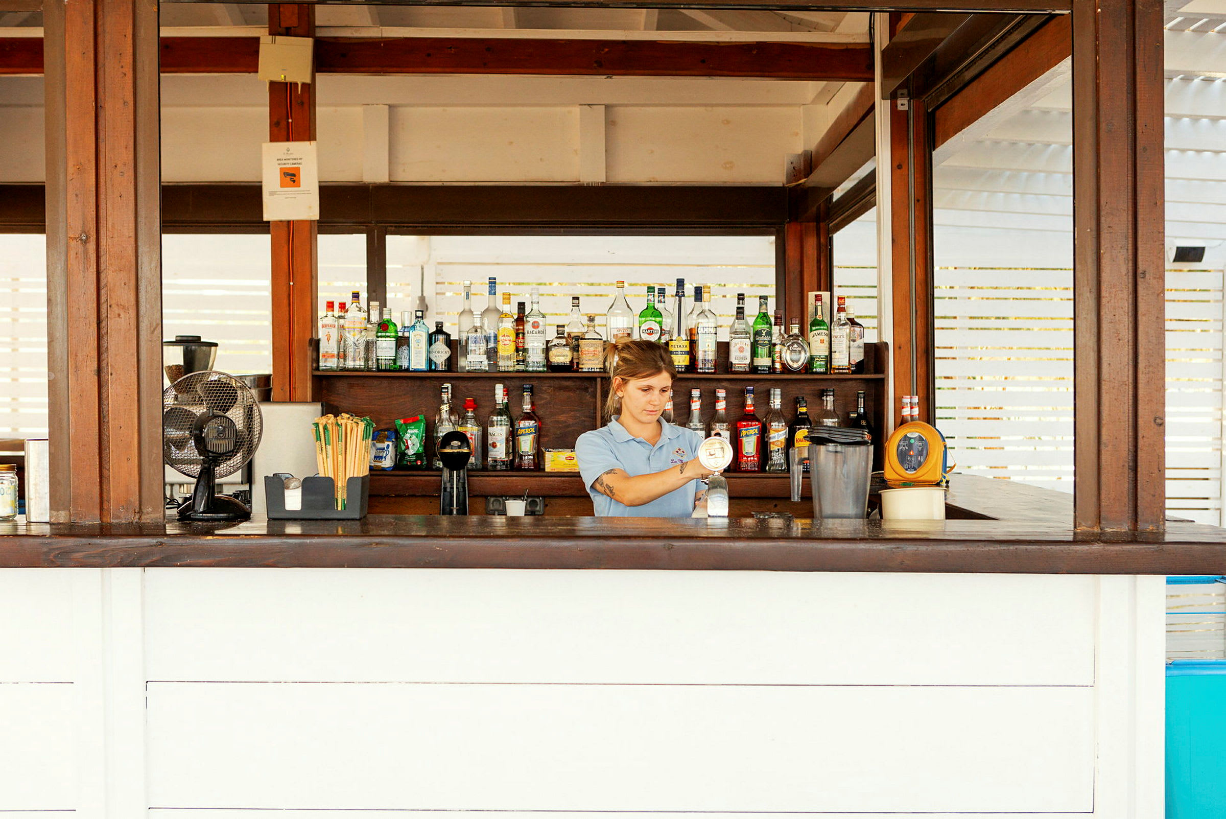 En bar med olika flaskor organiserade på hyllor bakom disken. (AI-genererad text)