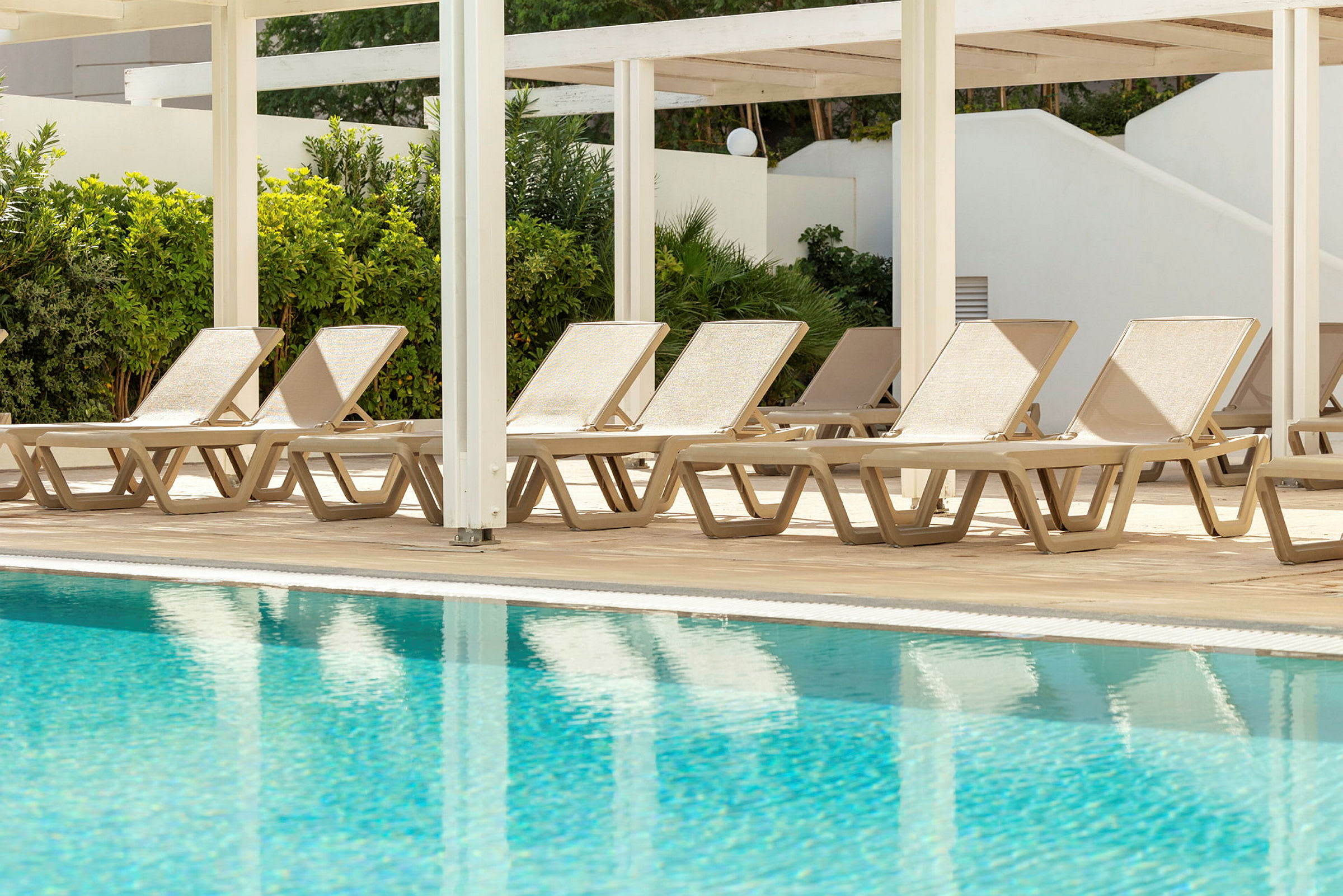 Solstolar vid en swimmingpool. (AI-genererad text)