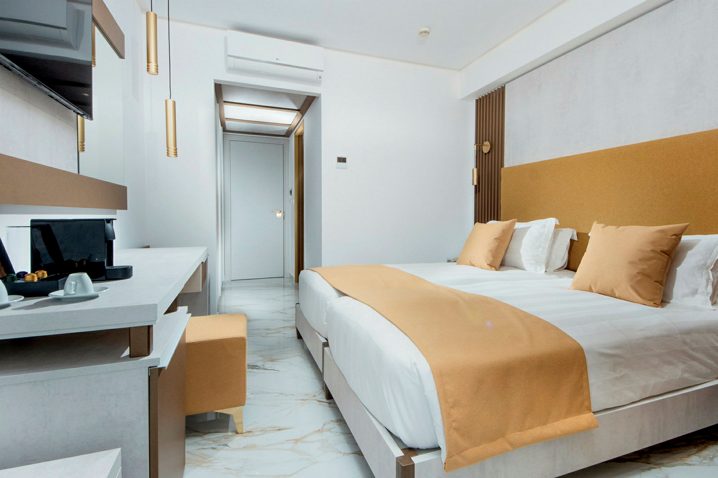 Ett modernt hotellrum med en stor säng, marmorgolv och en arbetsyta med kaffemaskin. (AI-genererad text)