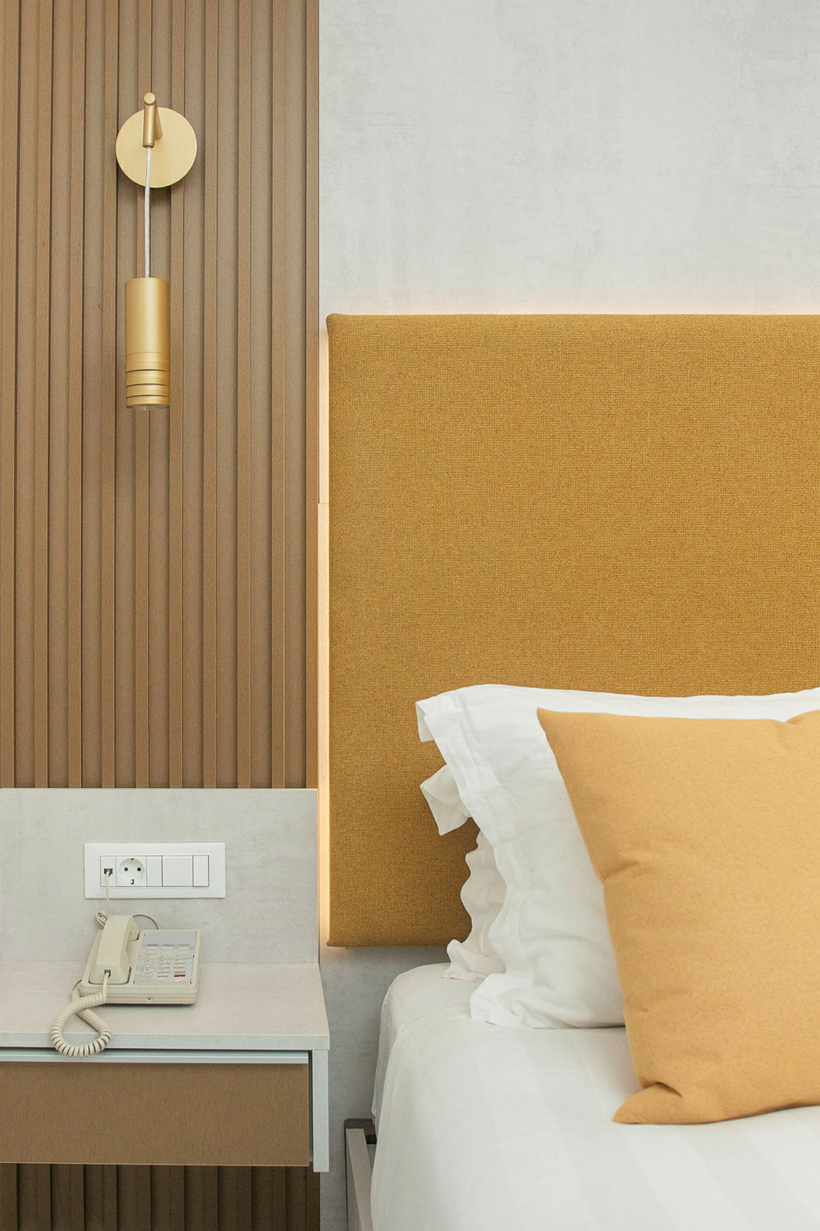 Hotellrum med brun panelvägg, gul sänggavel och inredningsdetaljer. (AI-genererad text)
