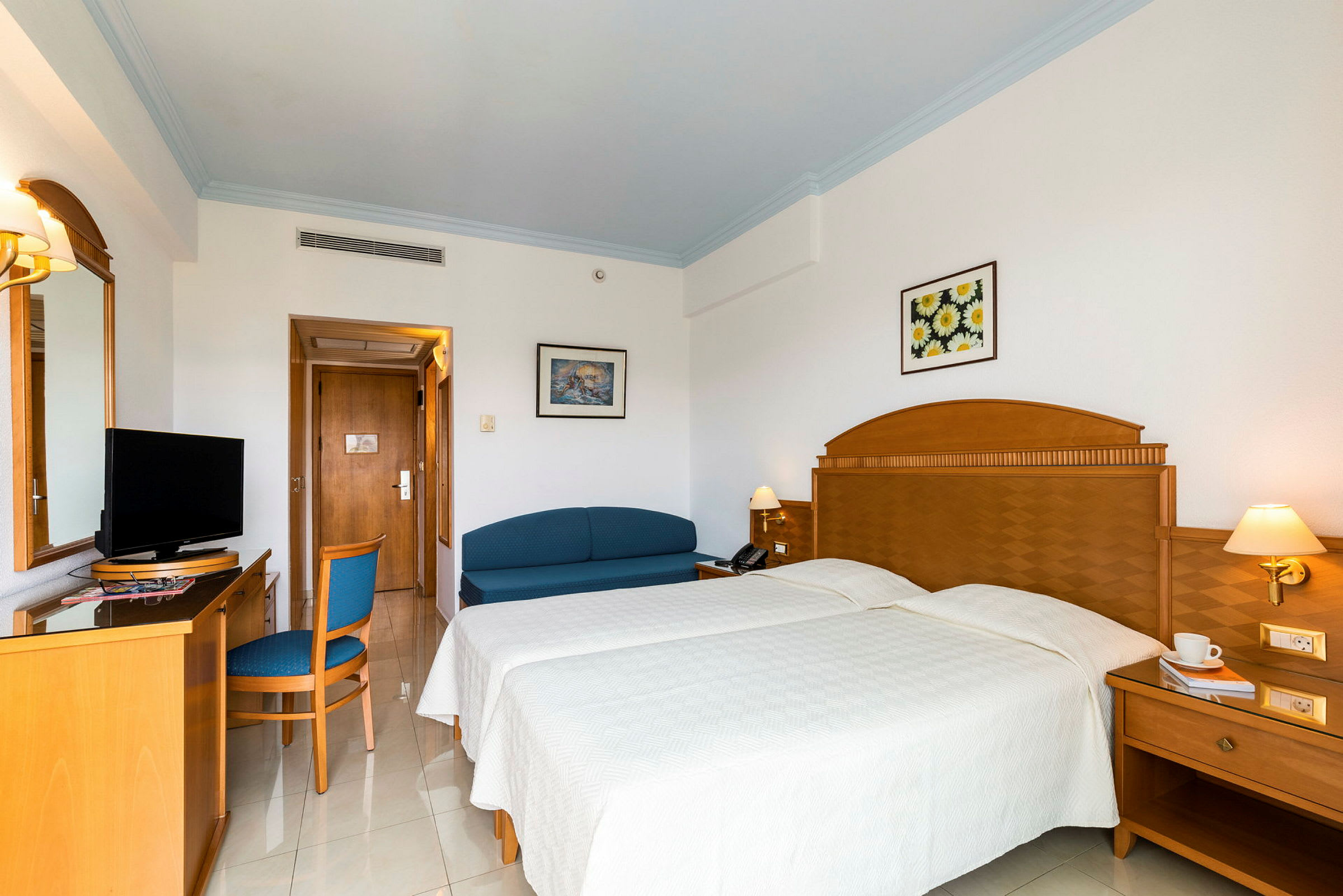 Hotellrum med två enkelsängar, ett skrivbord, en soffa och en TV. (AI-genererad text)