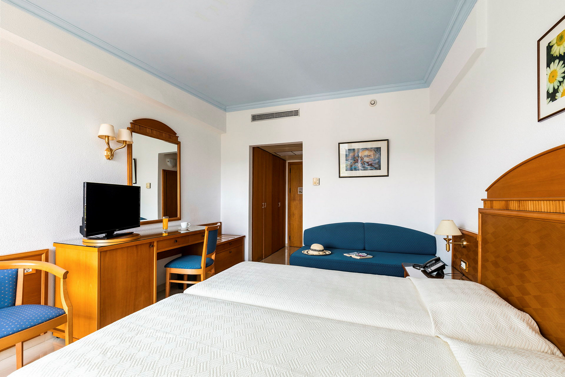 Ett hotellrum med en säng, en soffa, ett skrivbord och en TV. (AI-genererad text)
