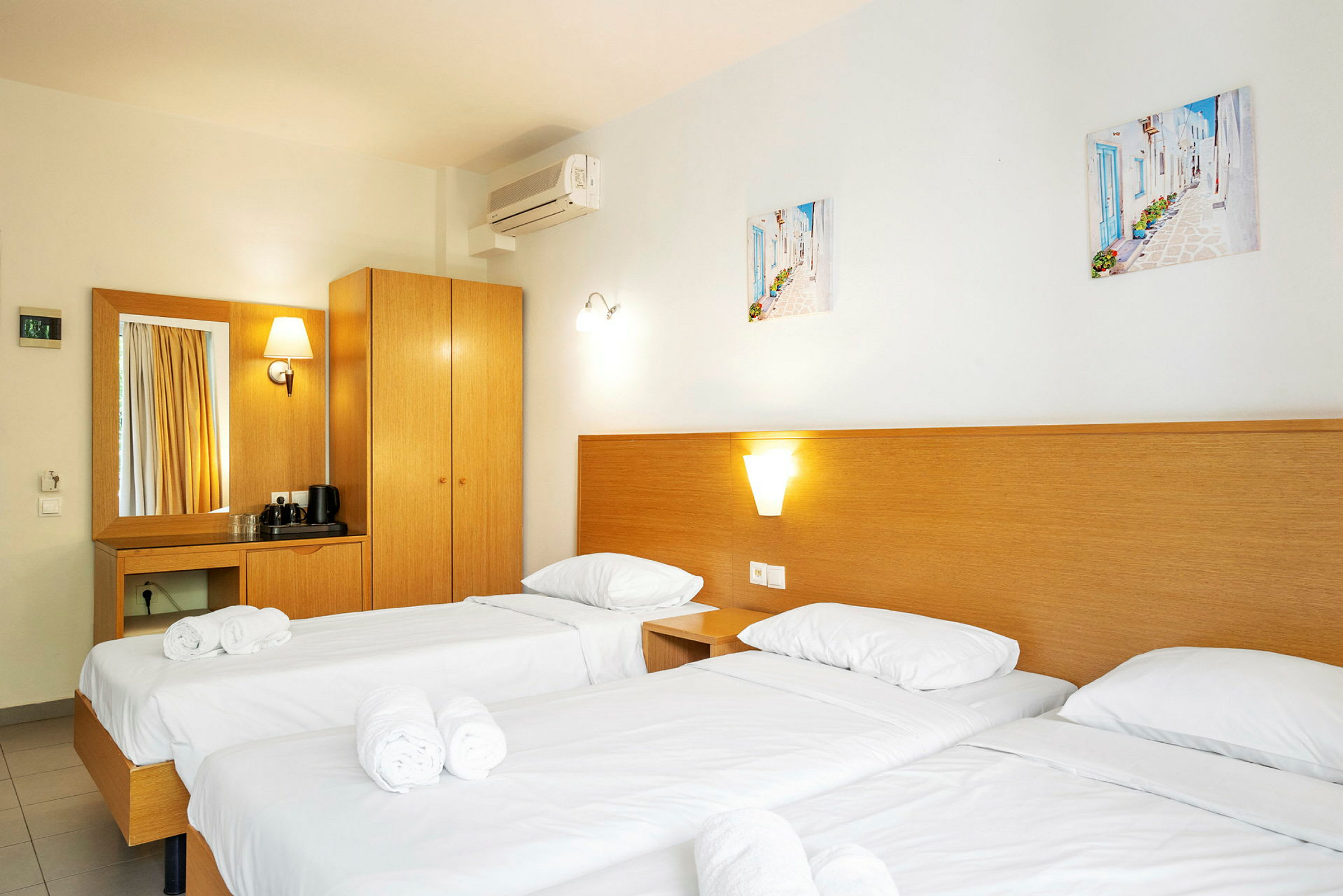 Hotellrum med tre enkelsängar, inredda med vita sängkläder och rullade handdukar. (AI-genererad text)