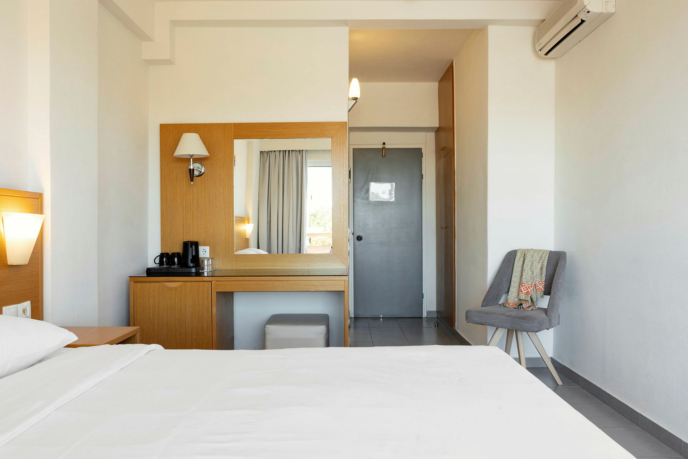 Ett hotellrum med en säng, ett bord och spegel för toalettartiklar, samt en stol vid sidan. (AI-genererad text)