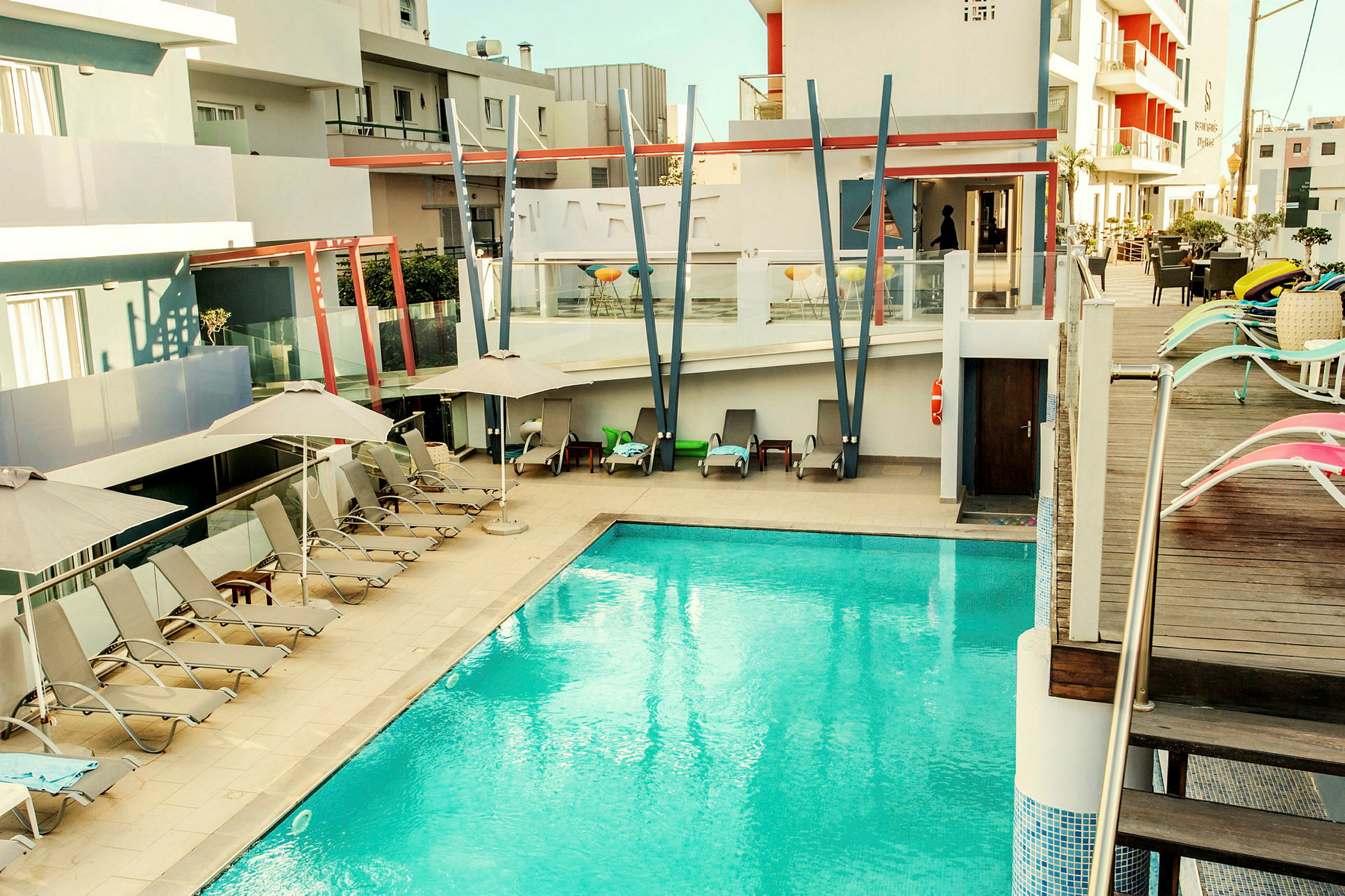 Utomhuspool vid ett modernt hotell med solstolar och parasoller. (AI-genererad text)
