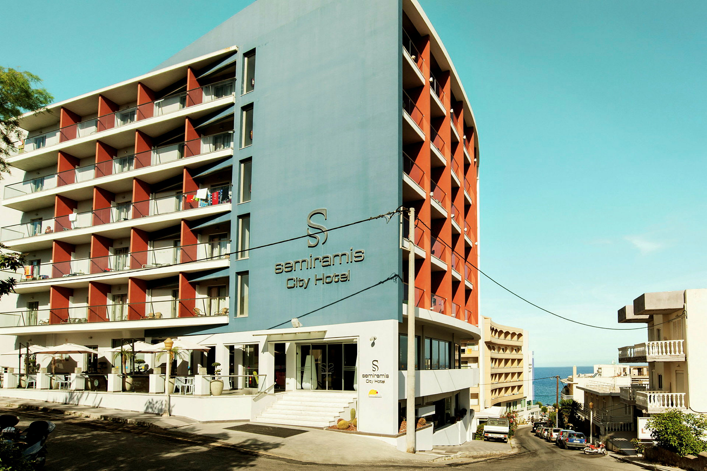 Modern hotellbyggnad med balkonger och entré. Blå himmel syns ovanför. (AI-genererad text)