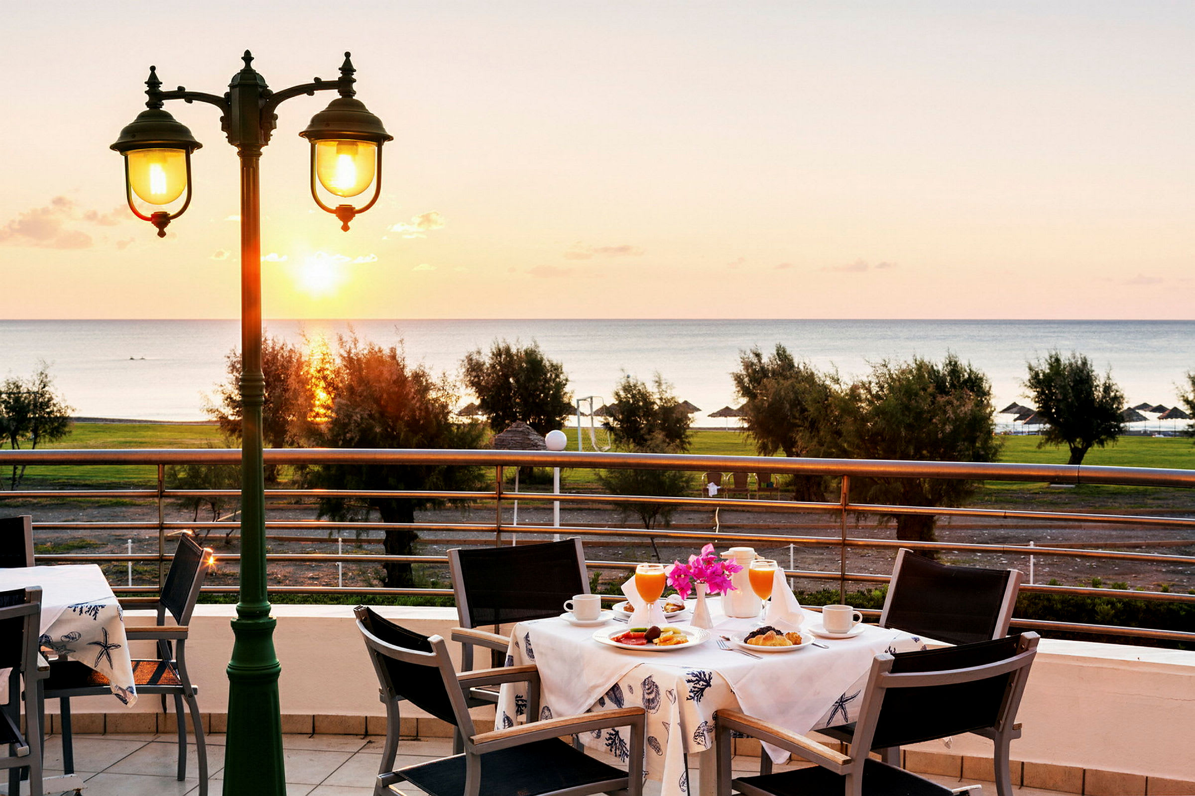 Utsikt över ett bord med frukostservering på en terrass med havet i bakgrunden. (AI-genererad text)