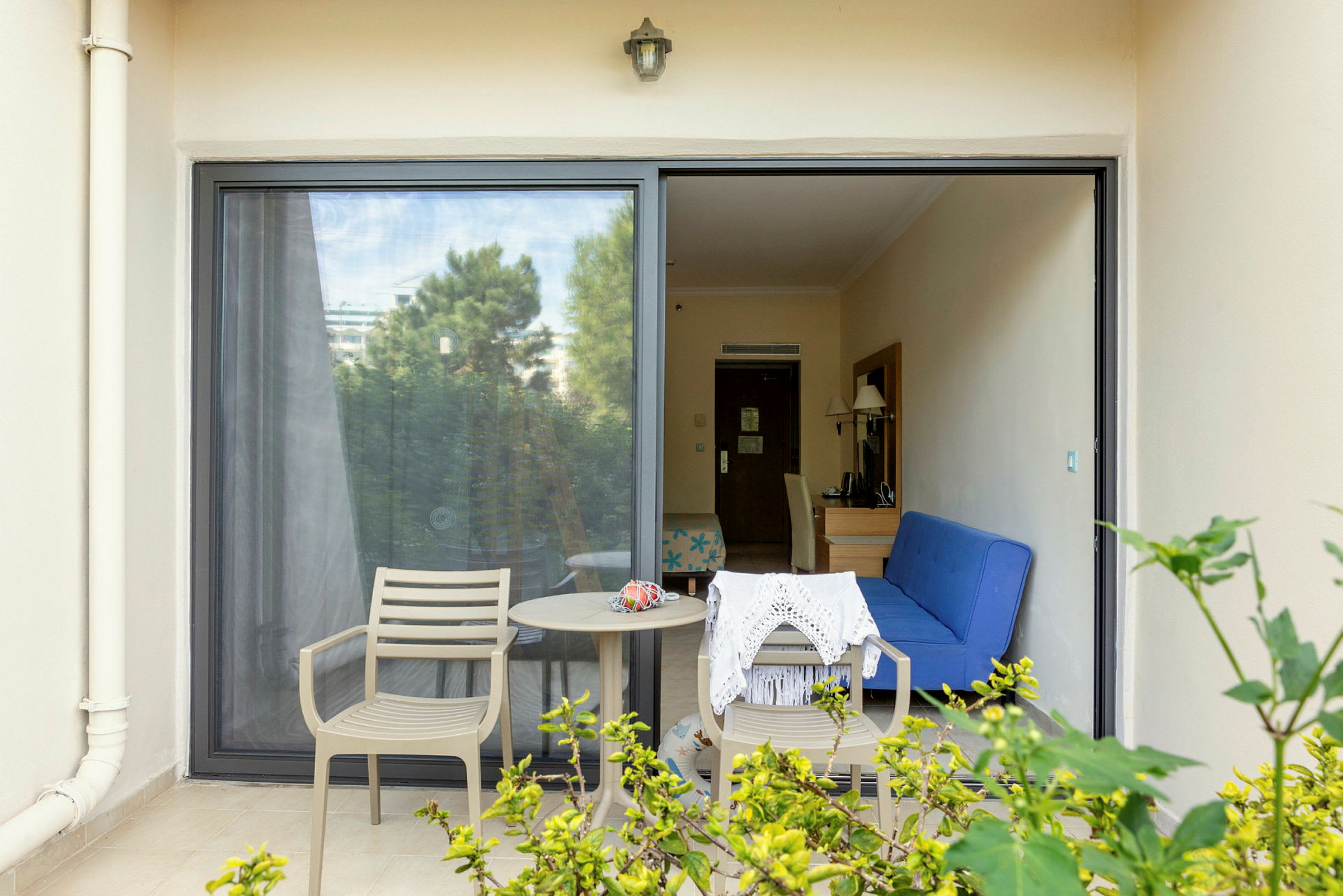 Bild på en terrass med två stolar, ett bord och utsikt in i ett hotellrum. (AI-genererad text)