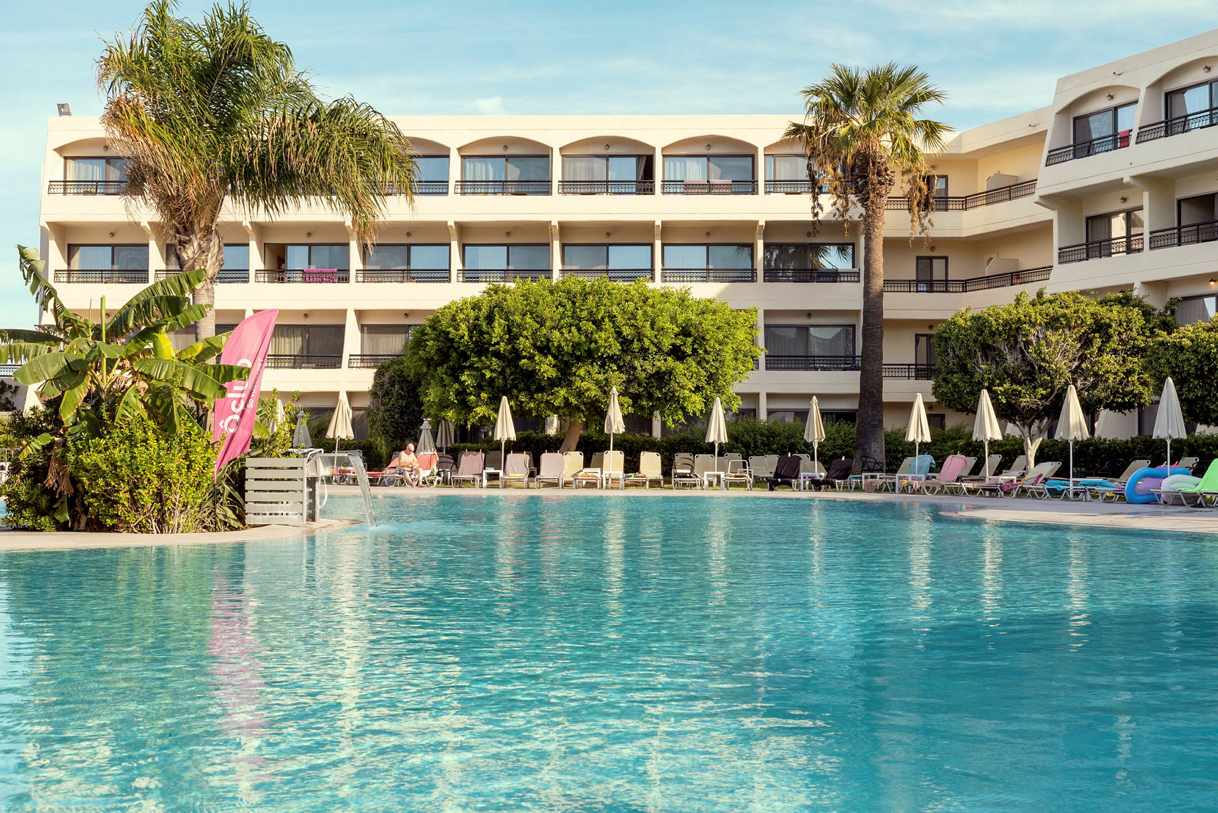 Hotell med pool och solstolar i förgrunden. (AI-genererad text)