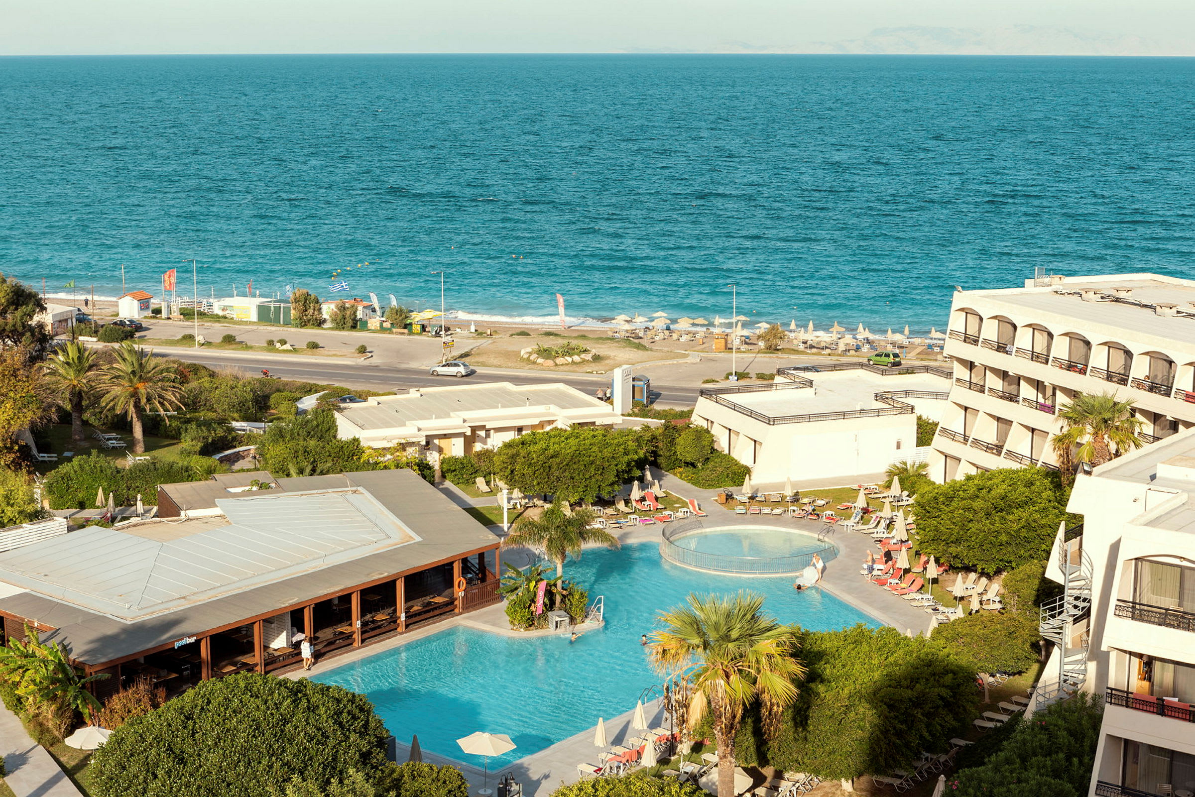 Bild av hotellområde med pool, grönska och utsikt mot havet. (AI-genererad text)