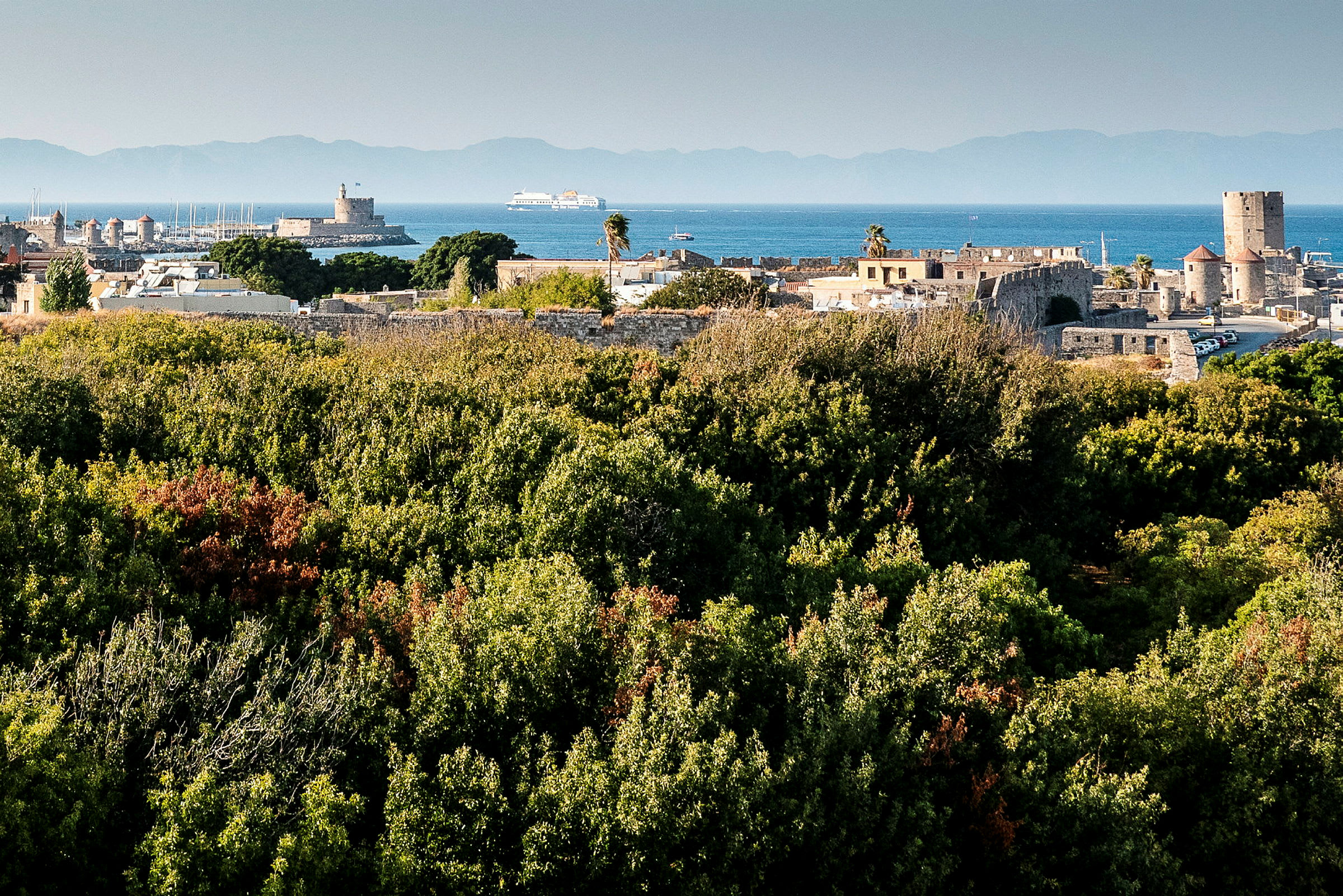 Utsikt över grönska och historiska byggnader vid havet. (AI-genererad text)