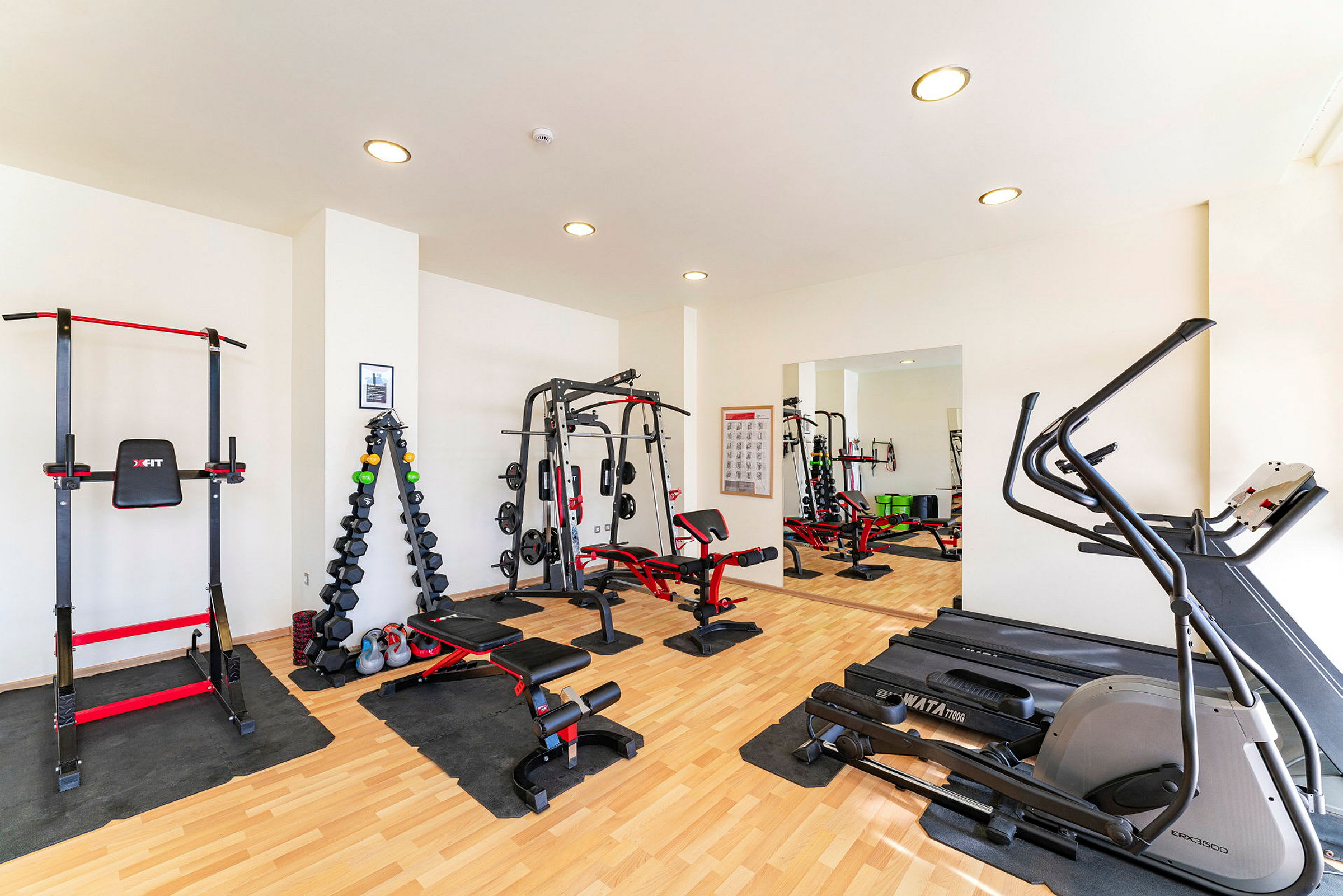 Ett gym med träningsutrustning såsom träningsmaskiner, vikter och bänkar. (AI-genererad text)