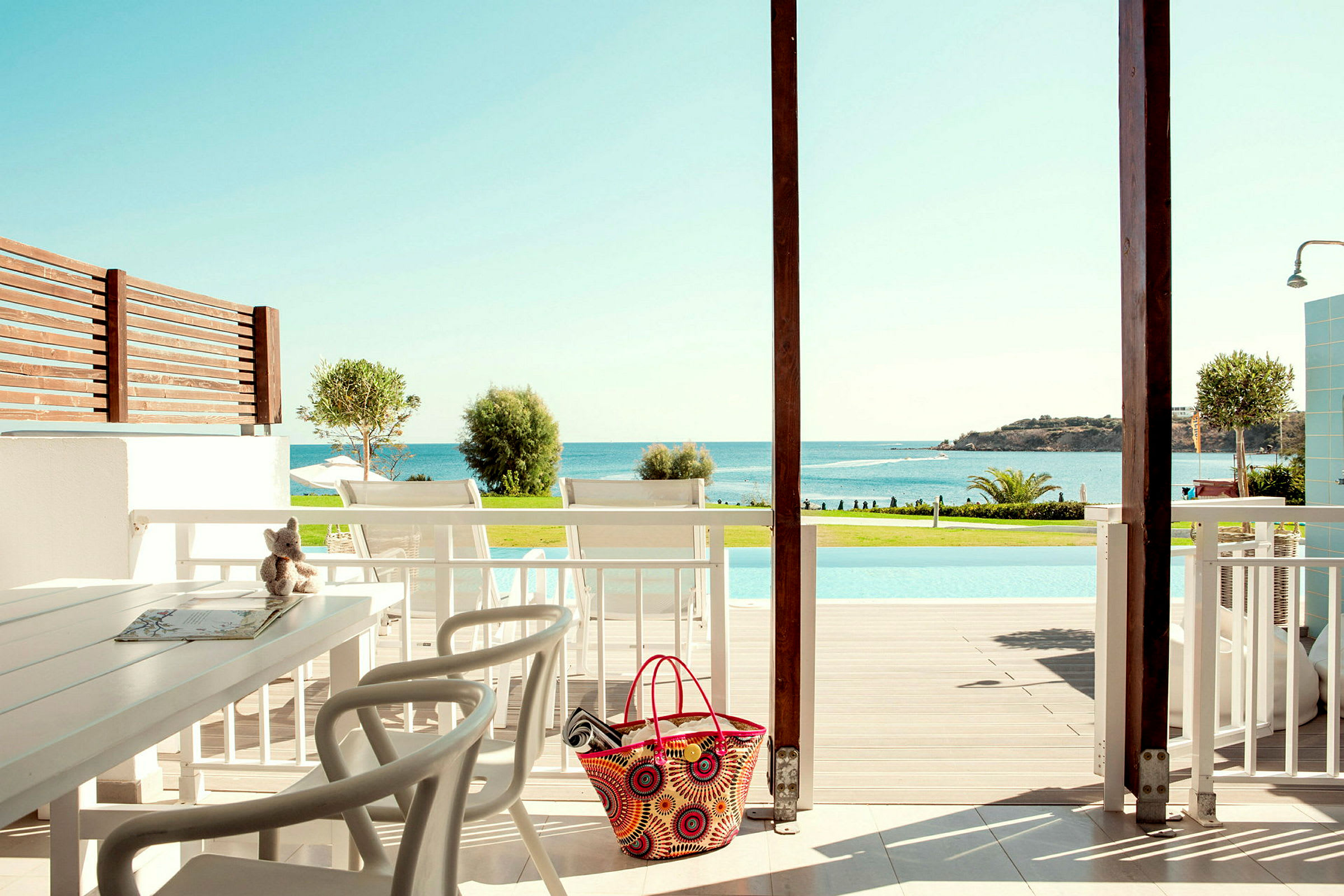 Utsikt från en terrass med sittgrupp mot en pool och havet. (AI-genererad text)