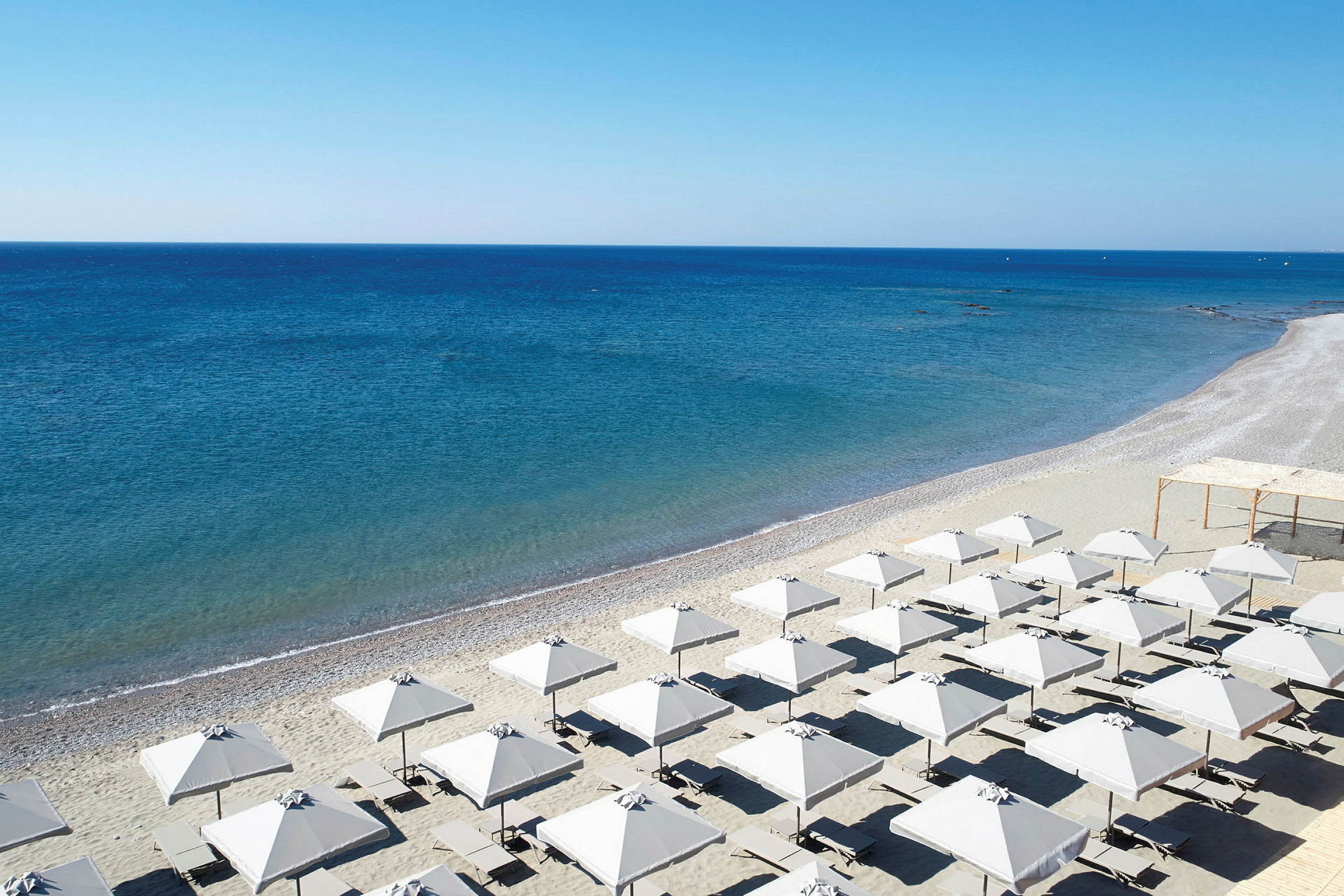 Strand med parasoller och solstolar vid havet. (AI-genererad text)