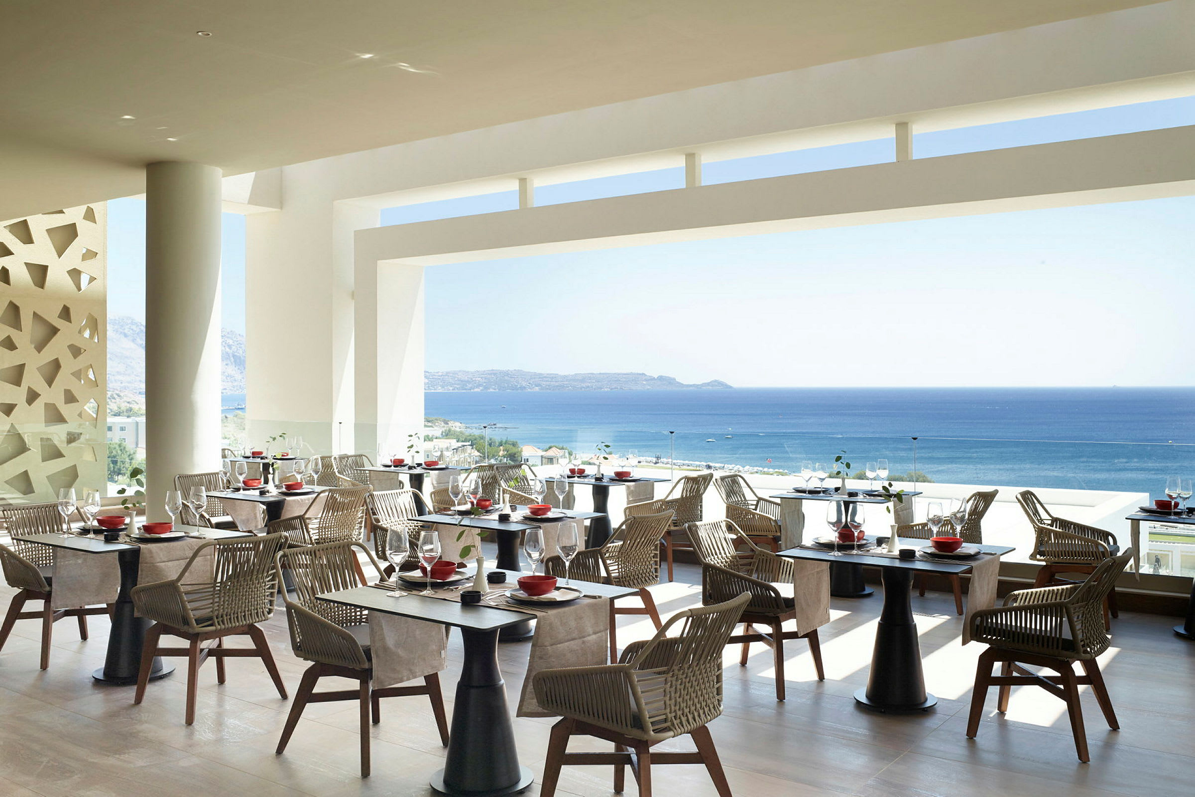 Bild av en restaurang med utsikt över havet, med bord och stolar i en modern inredning. (AI-genererad text)