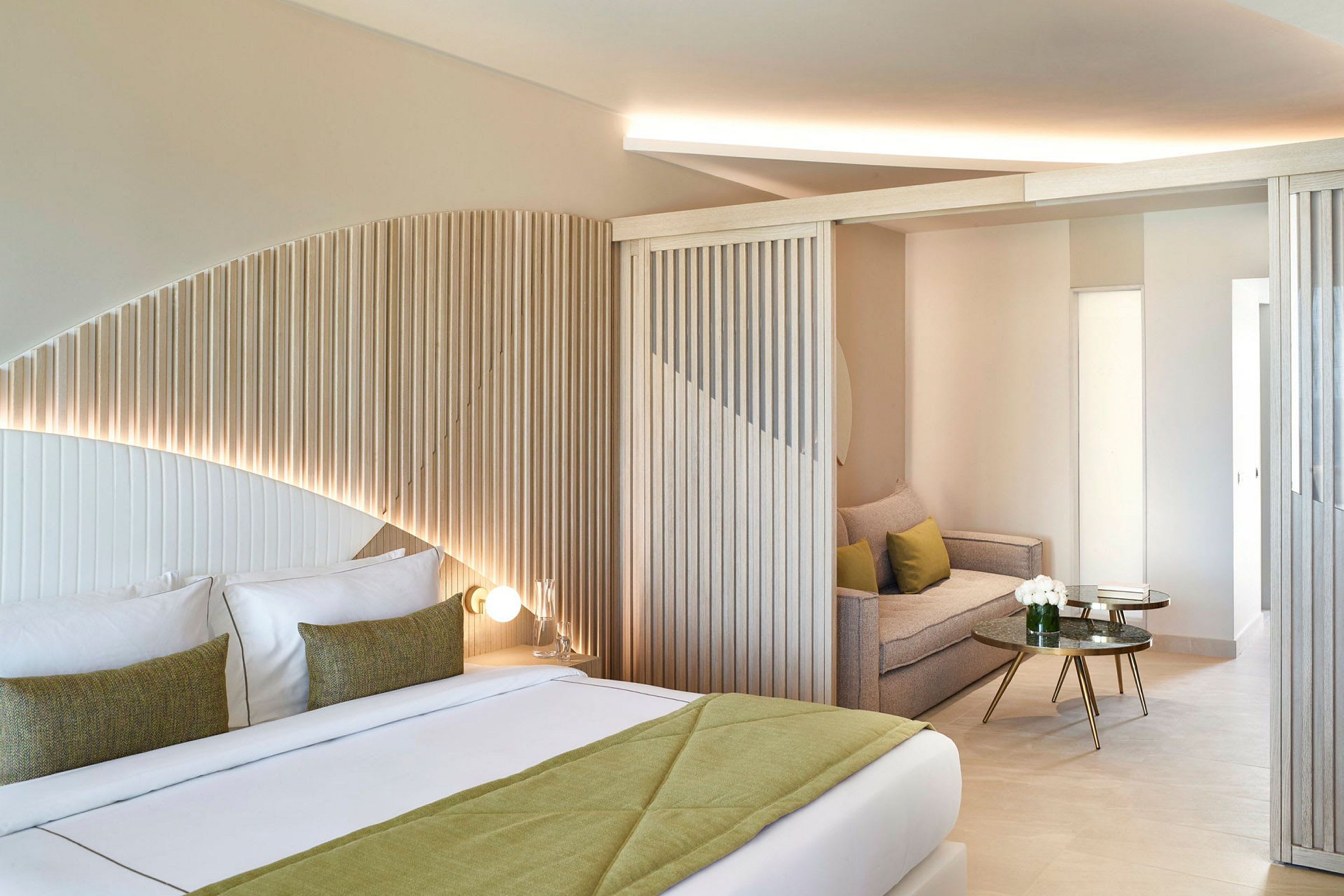 Modernt hotellrum med rundad träpanel, dubbelsäng och sittgrupp. (AI-genererad text)