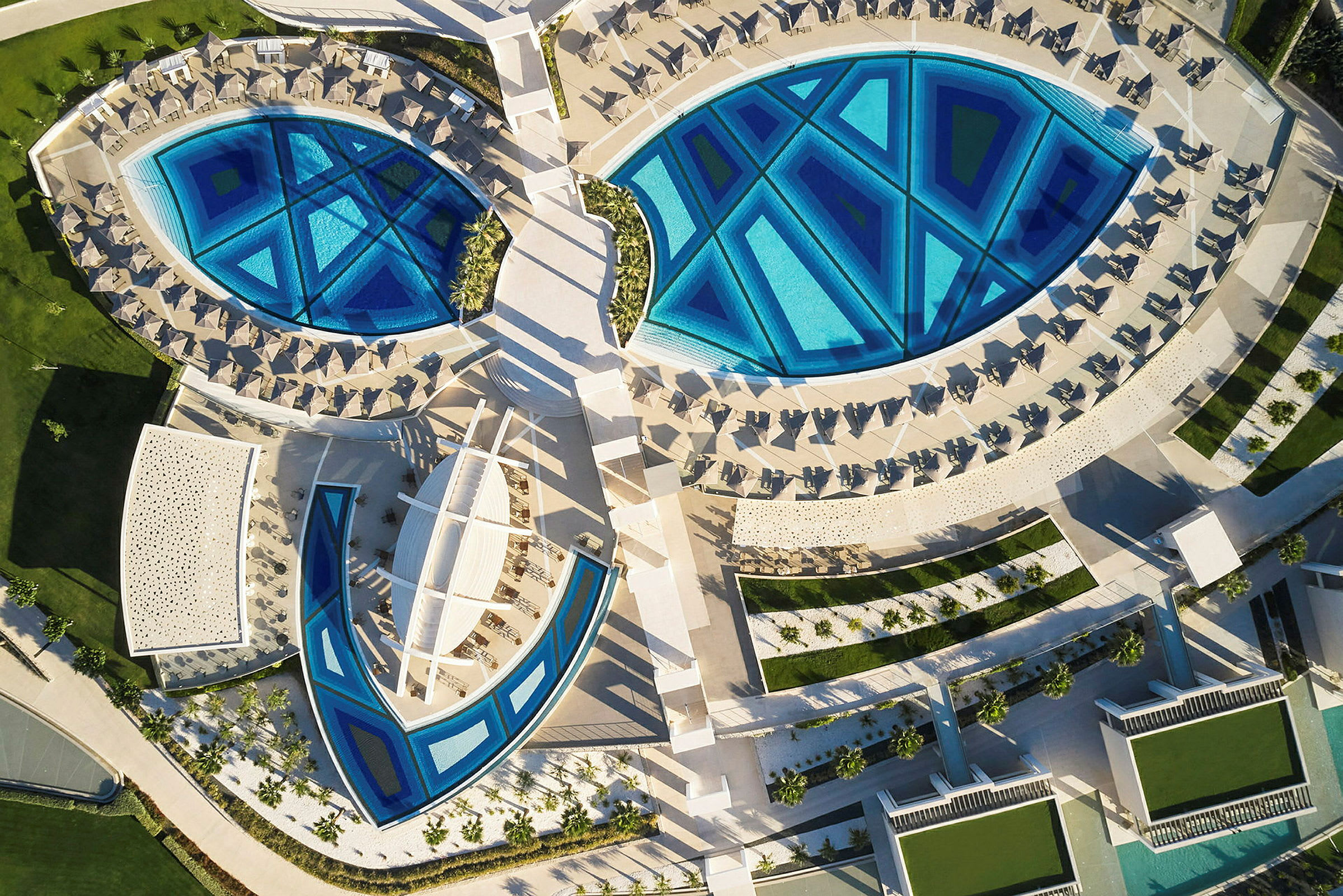 Flygvy över en resort med geometriska pooler och solstolar. (AI-genererad text)